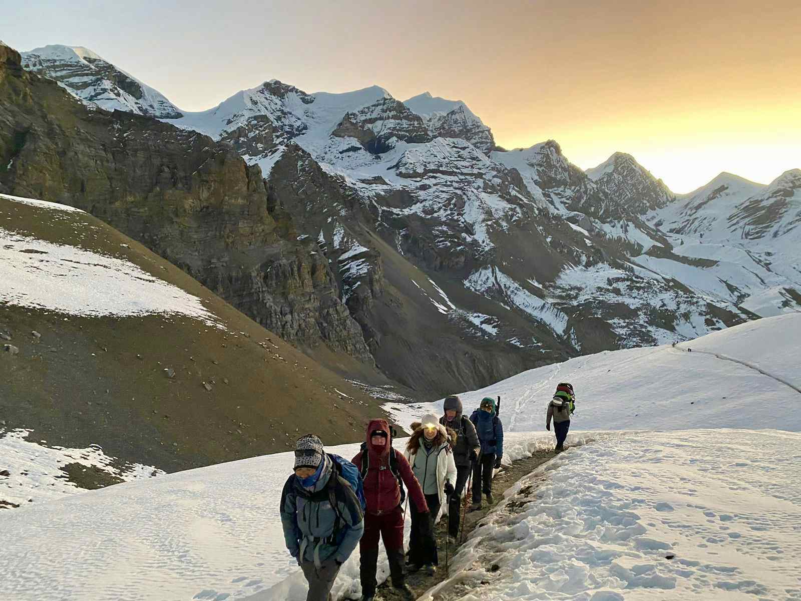 Trekkers on a trail in the snow at sunrise, Annapurna Circuit Trek, Nepal. 