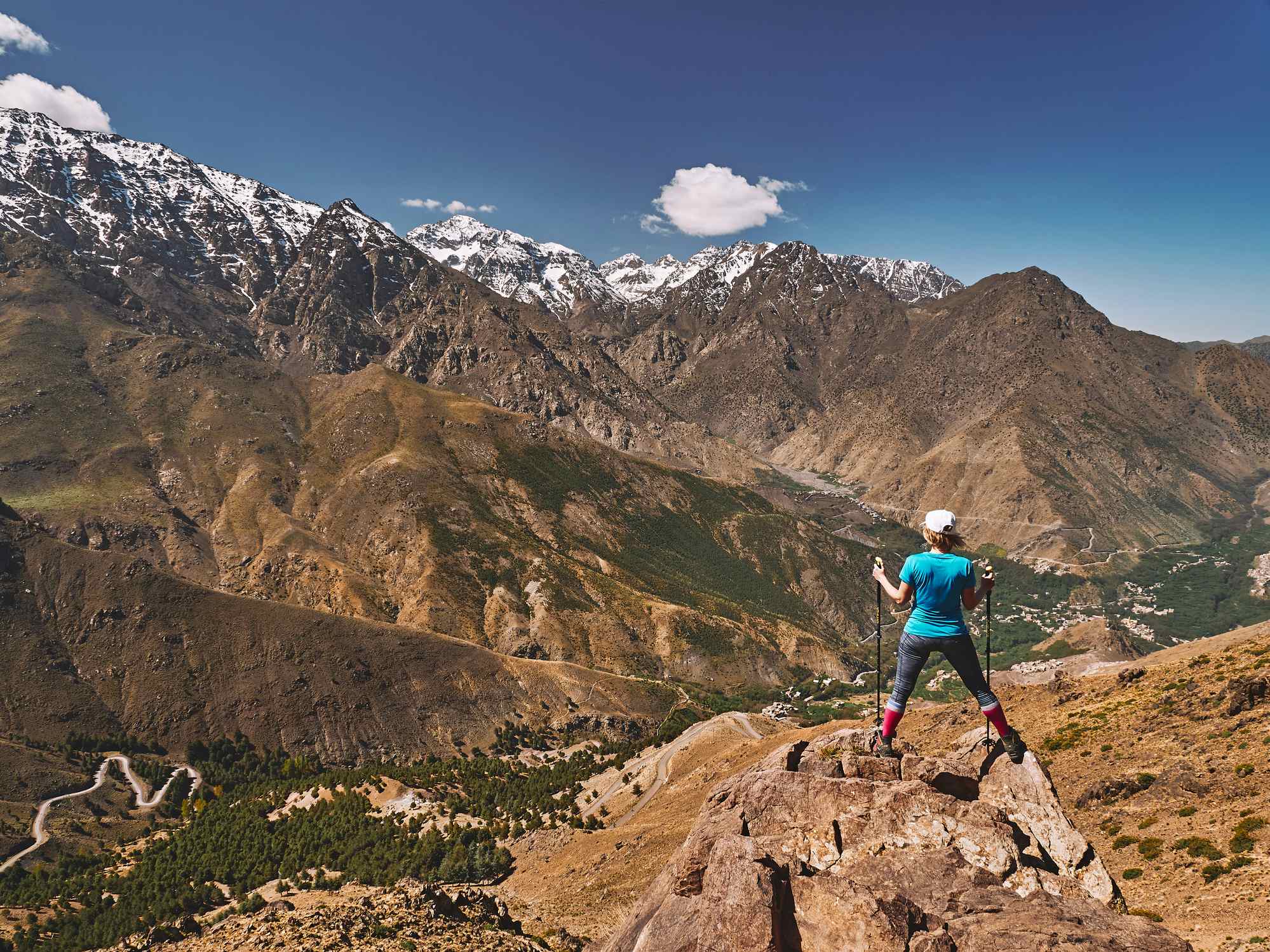 A female hiker stands upon a crag in the Atlas Mountains, Morocco. 