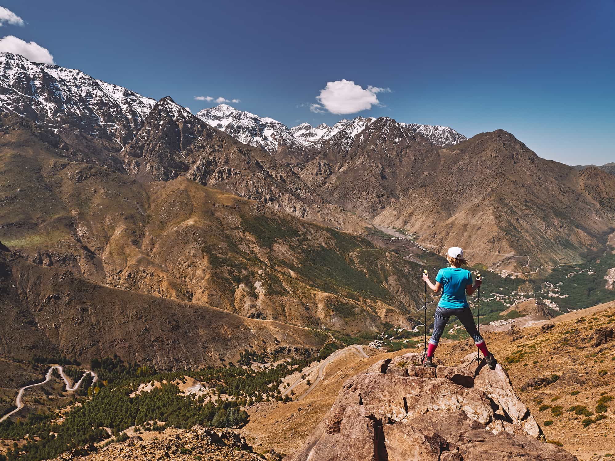 A female hiker stands upon a crag in the Atlas Mountains, Morocco.