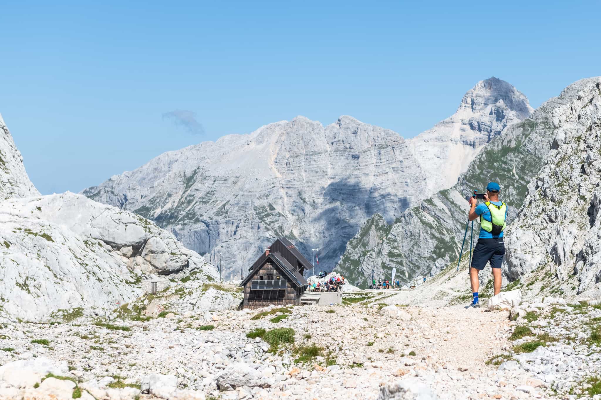 Hiker takes a photo of a mountain hut in dramatic mountain scenery in the Julian Alps