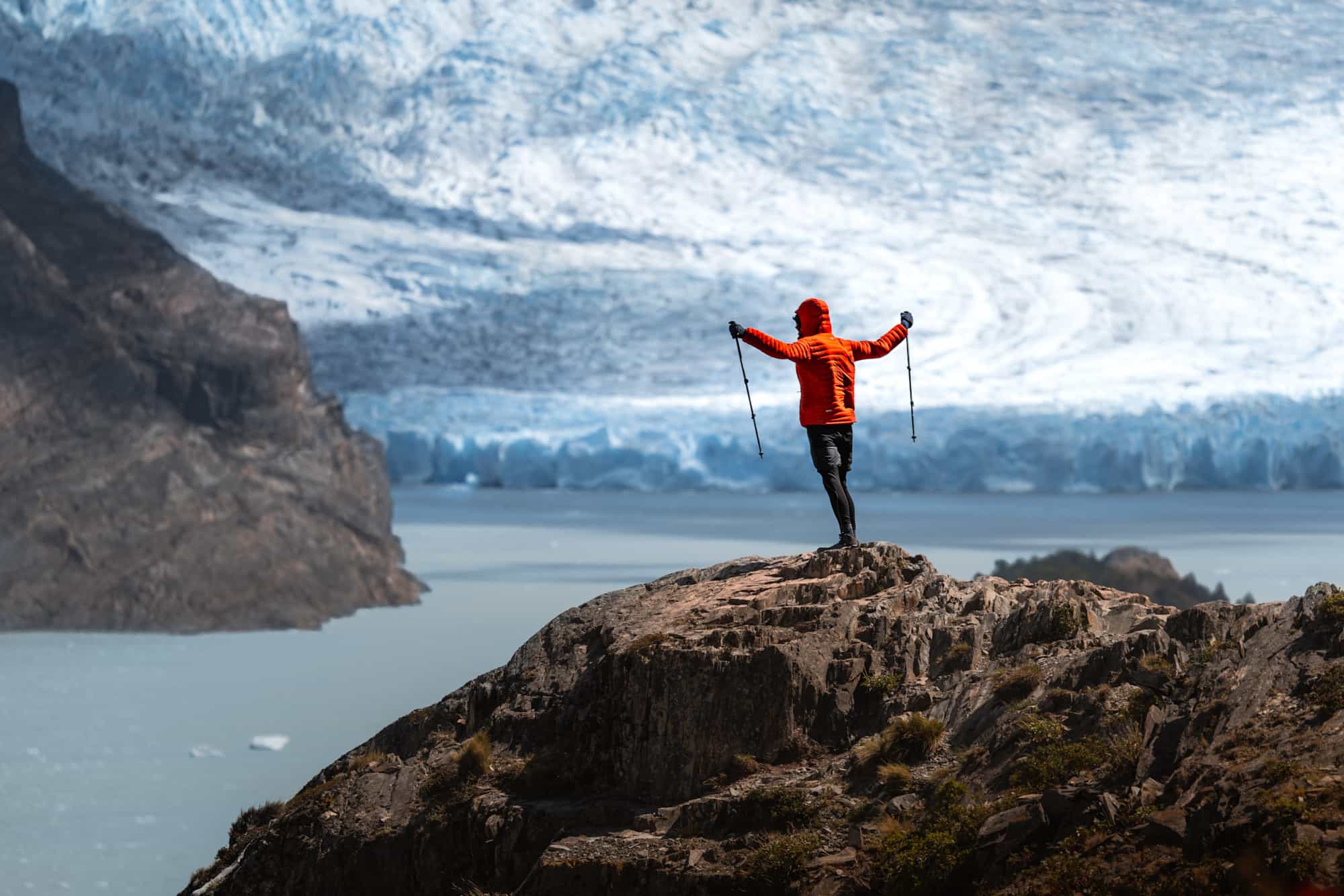 Hiker stands on a windy viewpoint above Glacier Grey
