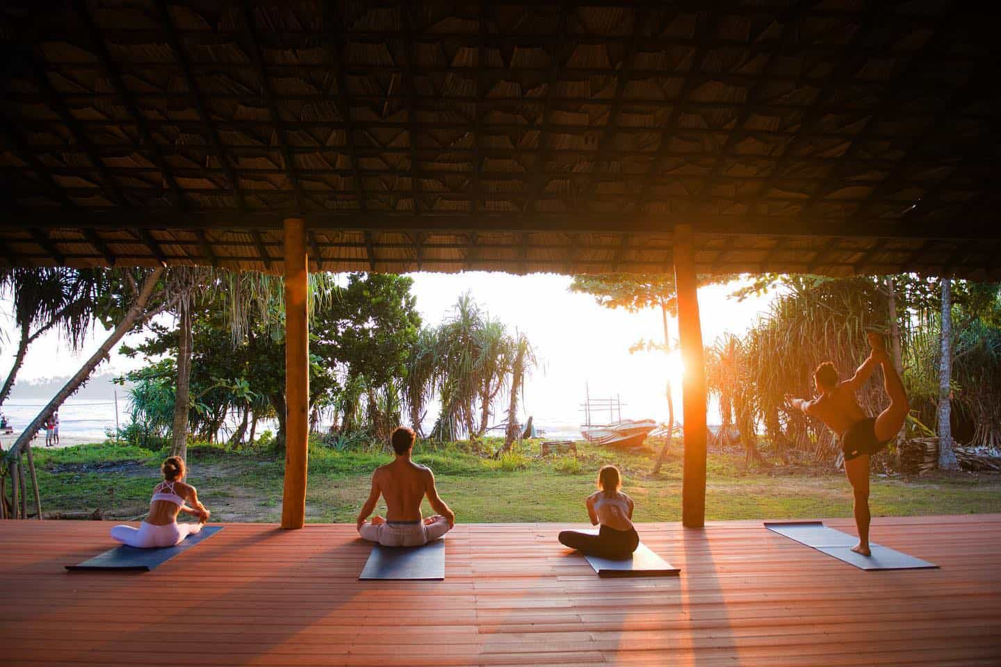 People practising yoga as the sun goes down at Talalla Retreat, Sri Lanka