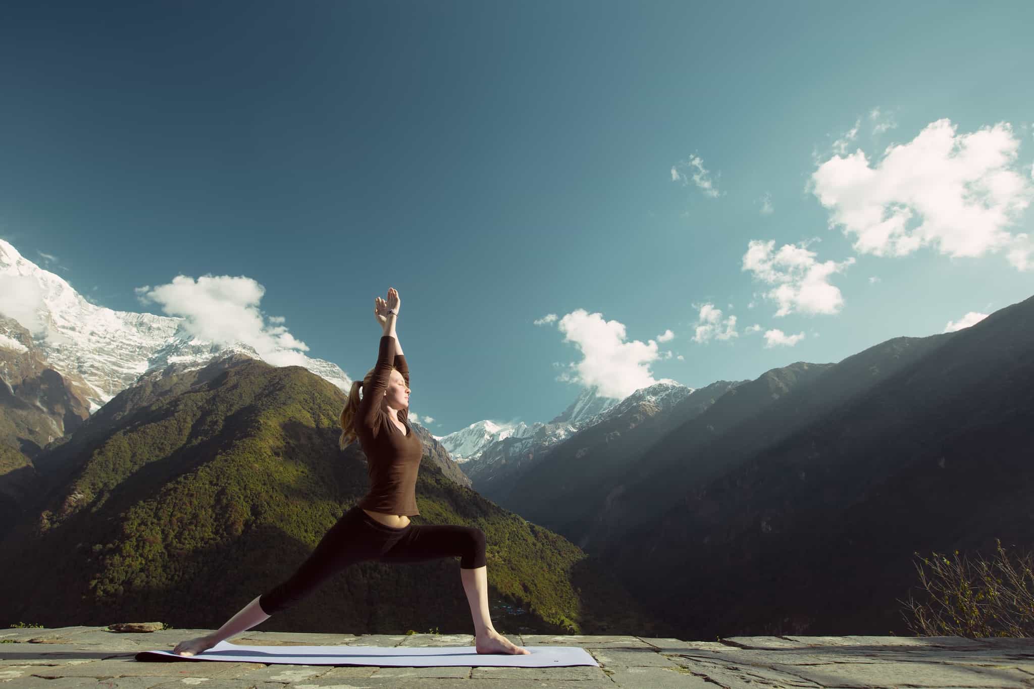 Women doing yoga pose with Himalayan mountains in the background