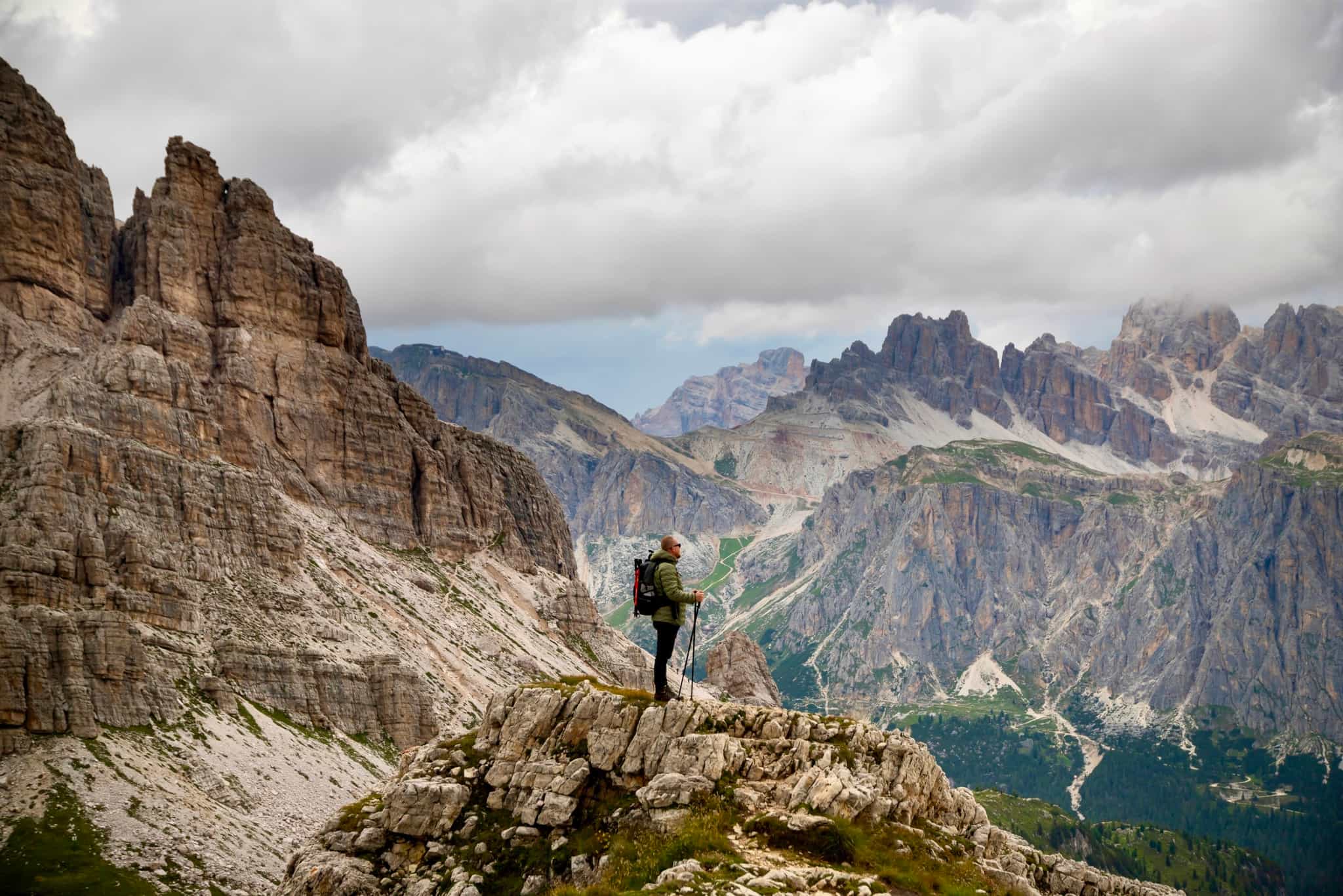 Male trekker with backpack in the mountains enjoying a picturesque view of the Dolomite peaks near Rifugio Nuvolau, Italy.