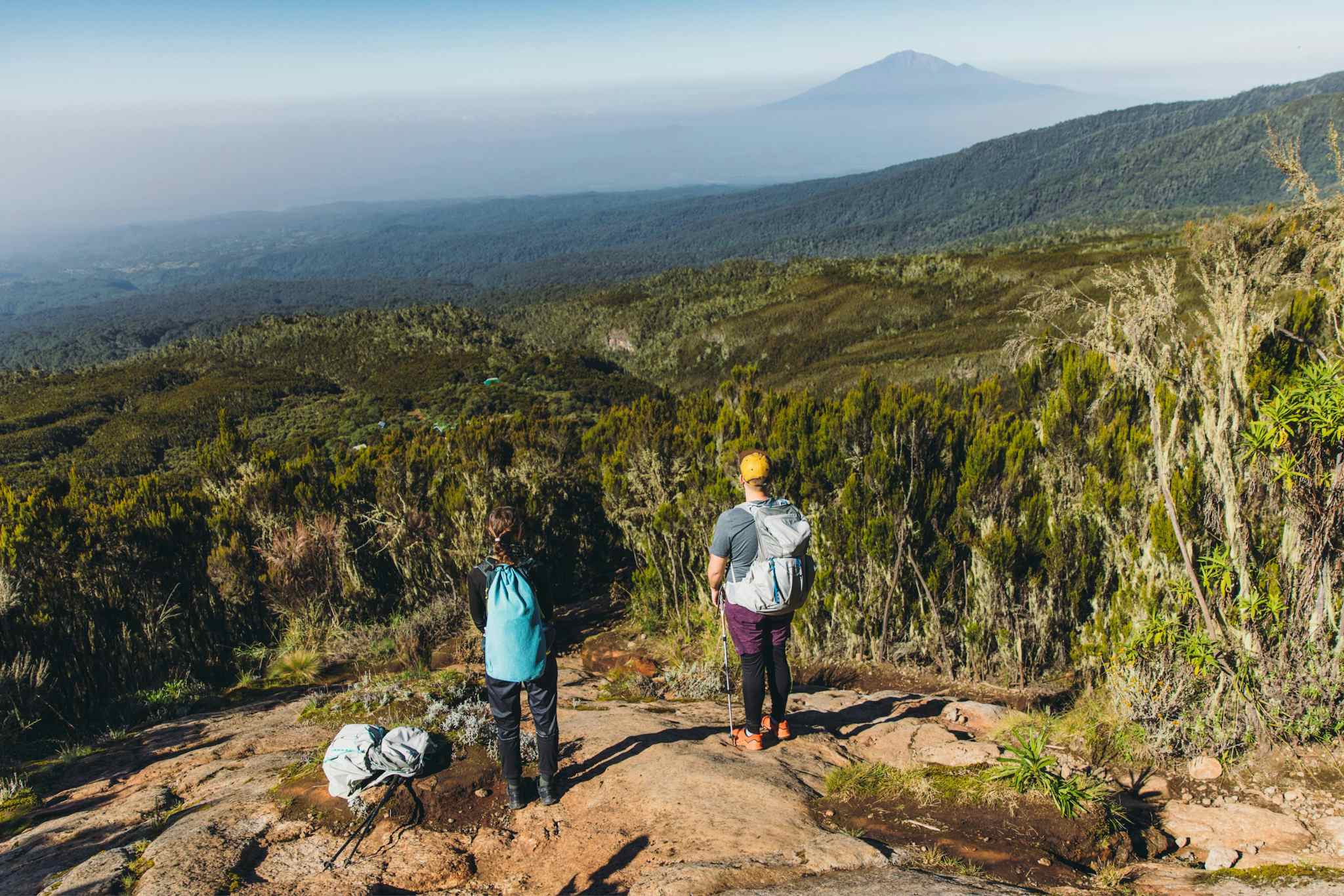 Hikers on Kilimanjaro with a view of Mount Meru, overlooking forests in Tanzania.