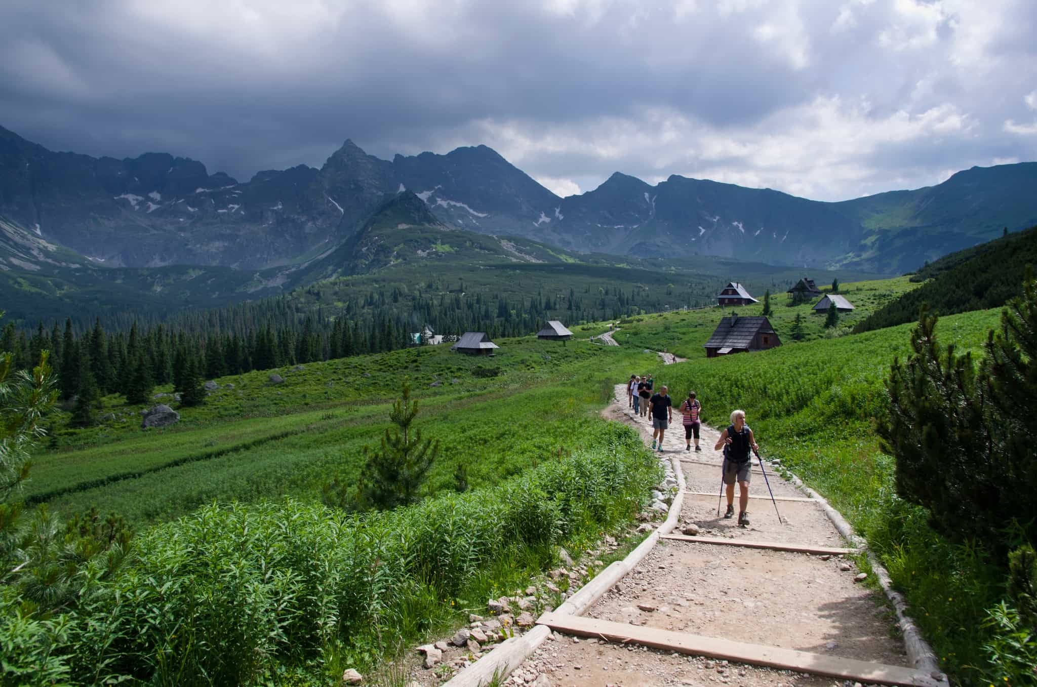 Hikers walking through a meadow with traditional mountian huts