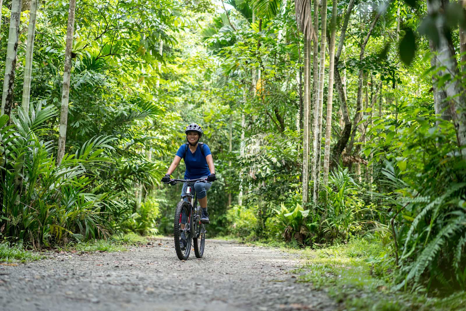 Woman e-mountain biking on a trail through the jungle