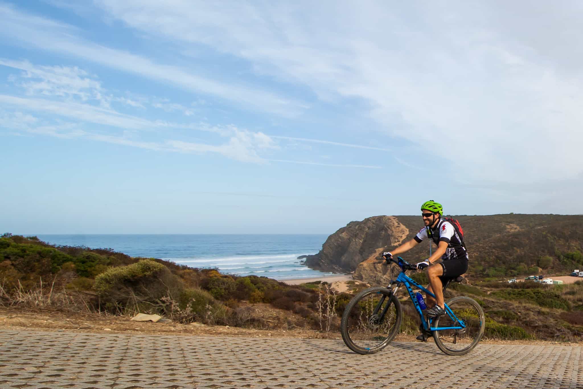 Cyclist pedalling past Carvalhal Beach in Portugal