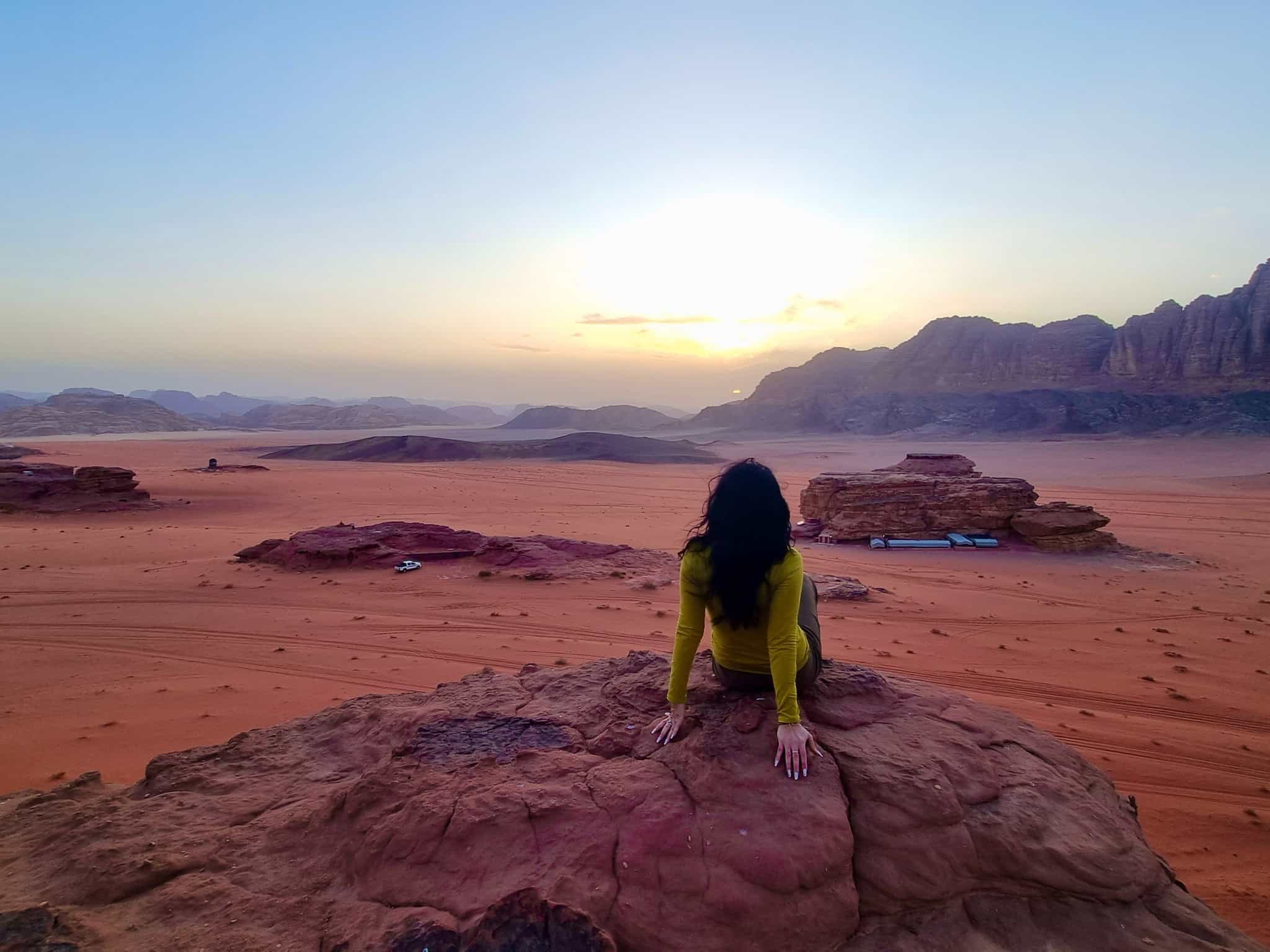 Woman sitting on a rock overlooking Wadi Rum desert in Jordan.