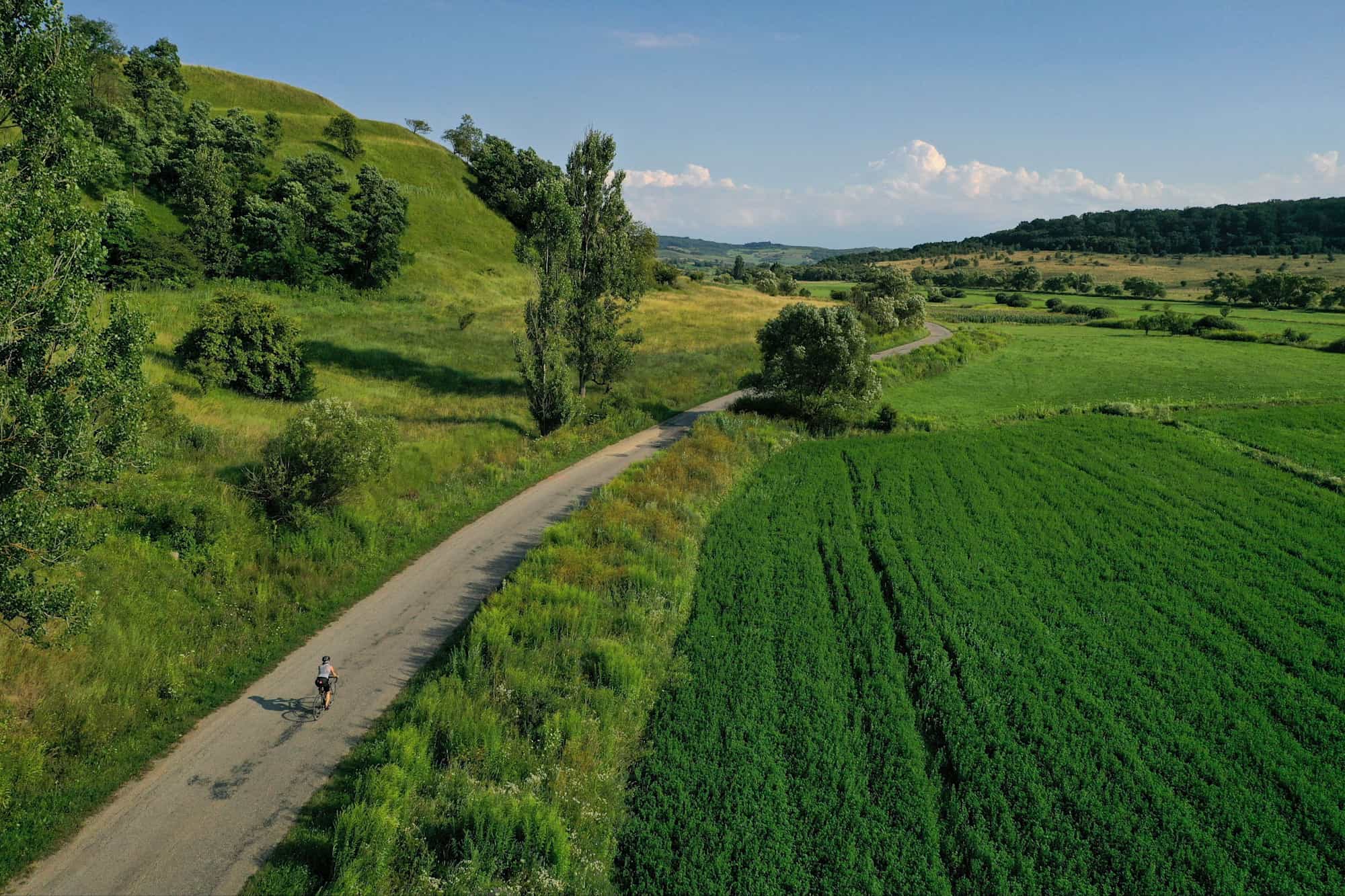 Drone photograph with cyclist riding on a beautiful winding road in Transylvania, Romania, in summer season