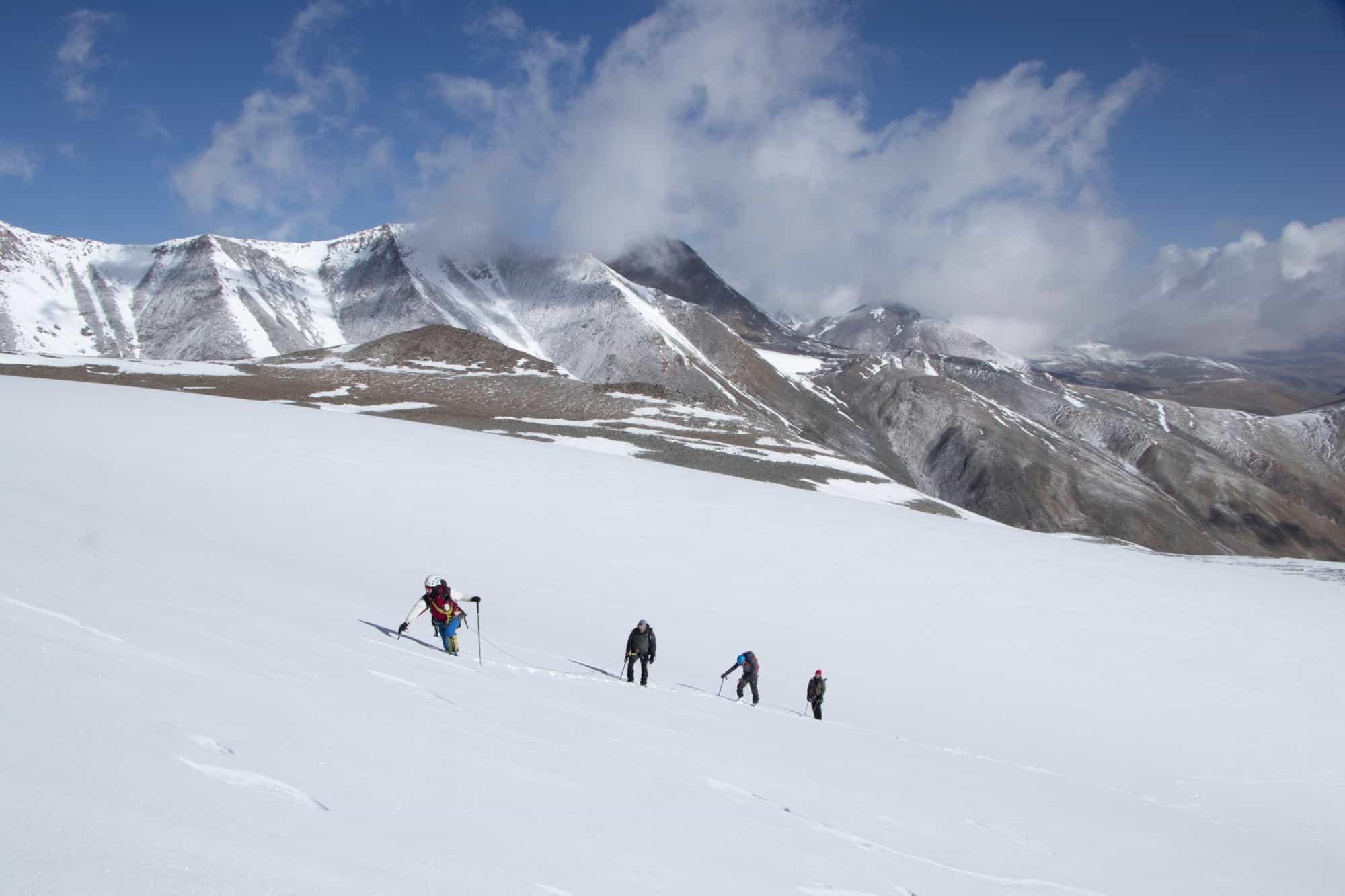 Four climbers ascending the snow fields of UT Kangri in Ladakh, India