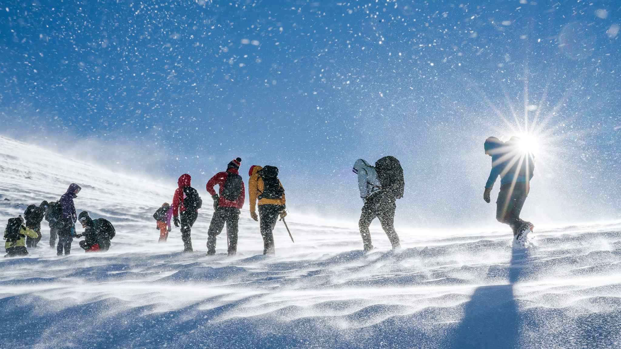 A group of hikers trek through the snow towards the summit of Mount Toubkal, Morocco.