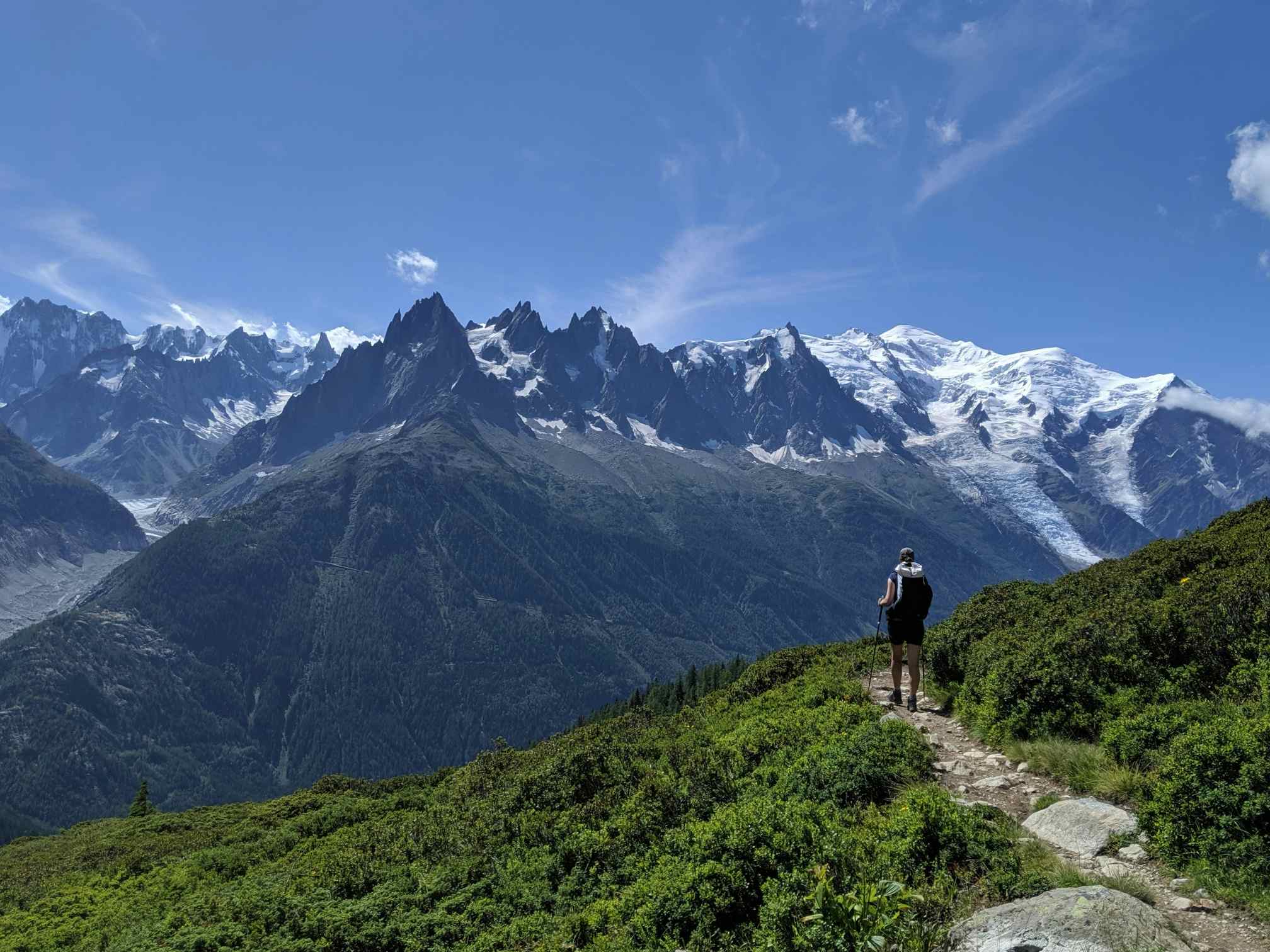 Hiker on the Tour du Mont Blanc trail, France. Photo: Canva - https://www.canva.com/photos/MADqjk6b0Gg-a-hiker-walking-on-a-path-during-the-famous-trek-tour-du-mont-blanc-beautiful-alpine-view-on-snowy-mountains-with-blue-sky-on-a-sunny-morning/