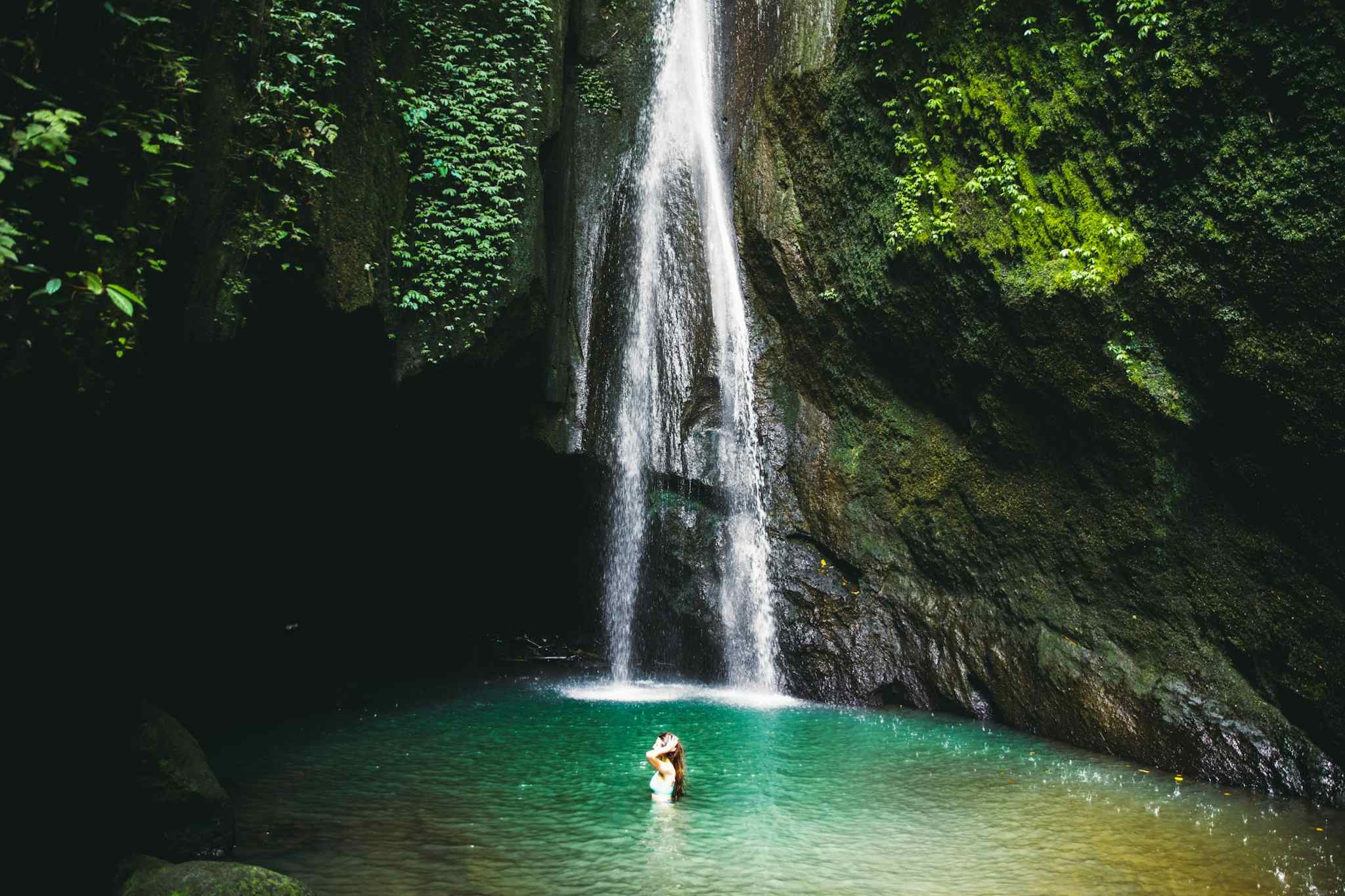 Girl swimming in waterfall pool in Bali, Indonesia. 