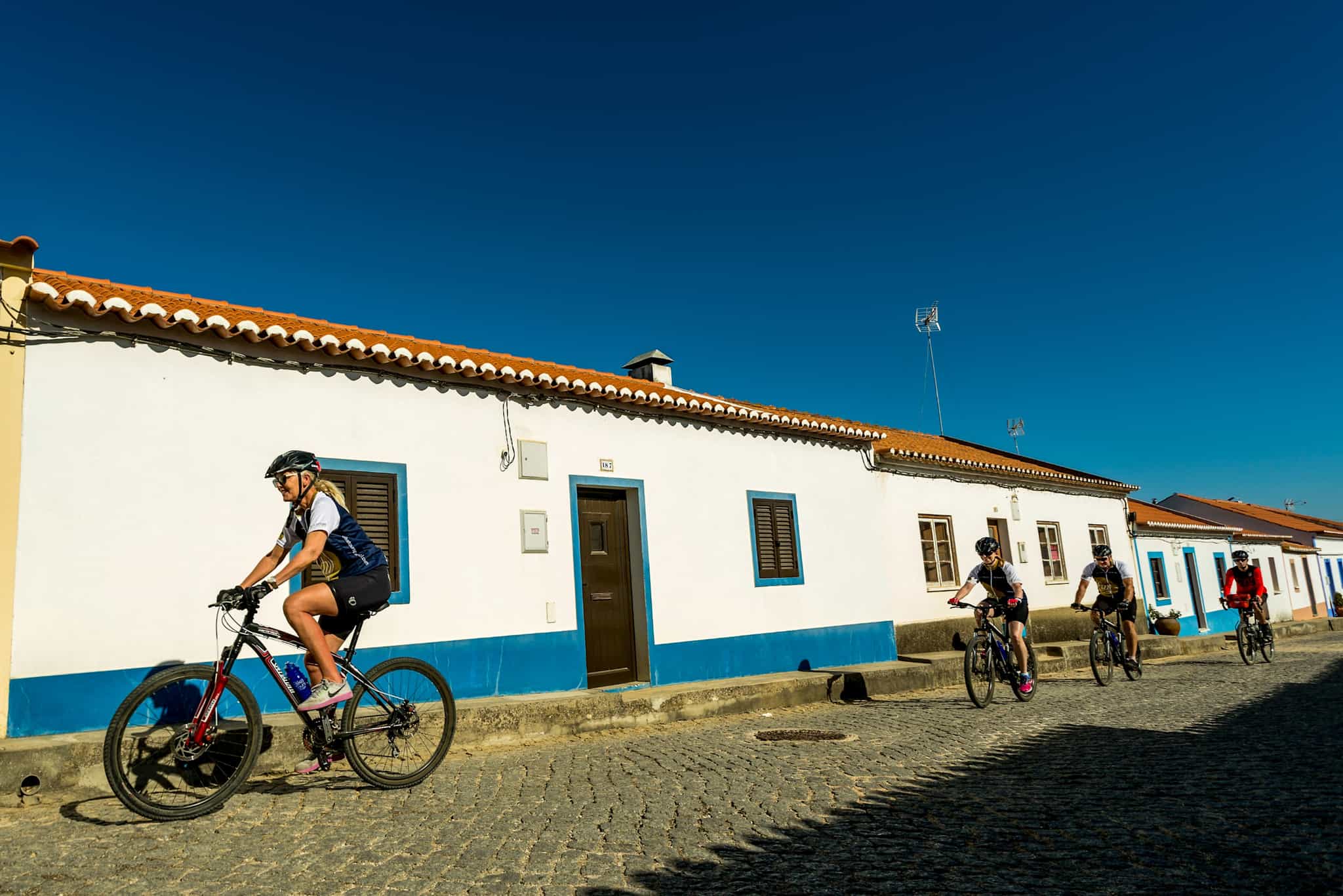 Cycling past traditional houses in Milfontes, Portugal