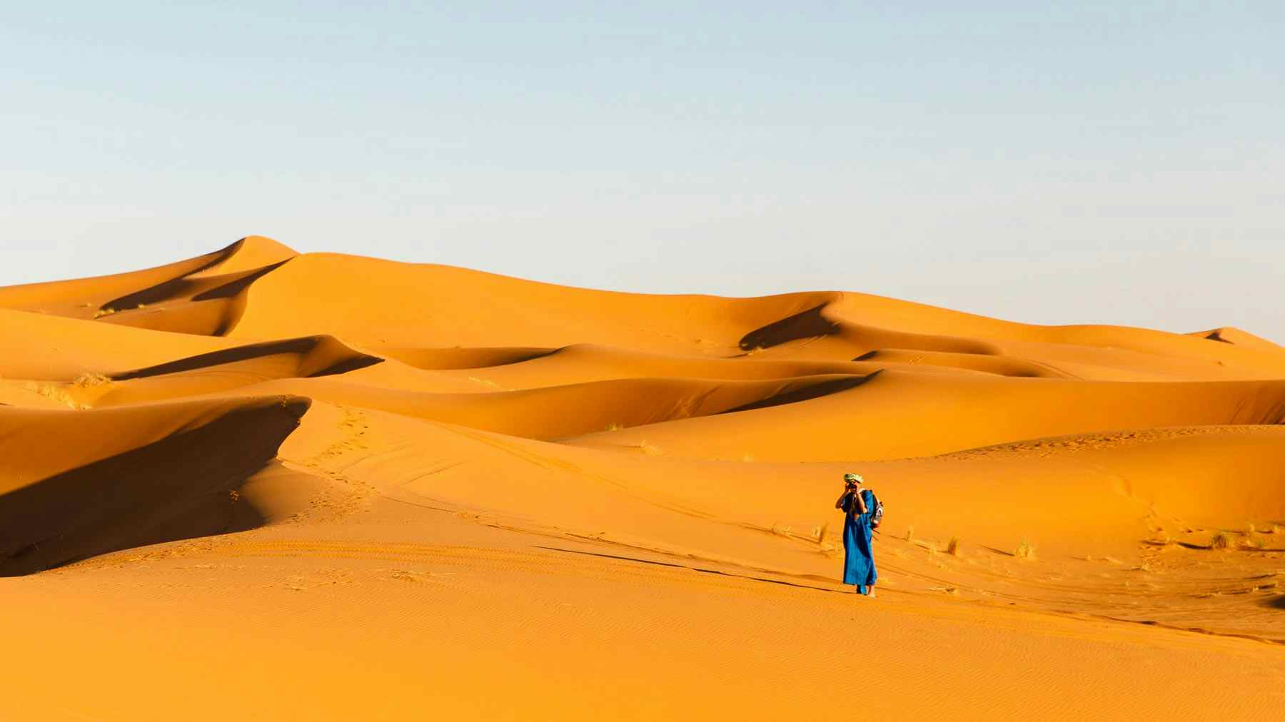 A Berber stands amongst the dunes in the Sahara Desert, Morocco. 