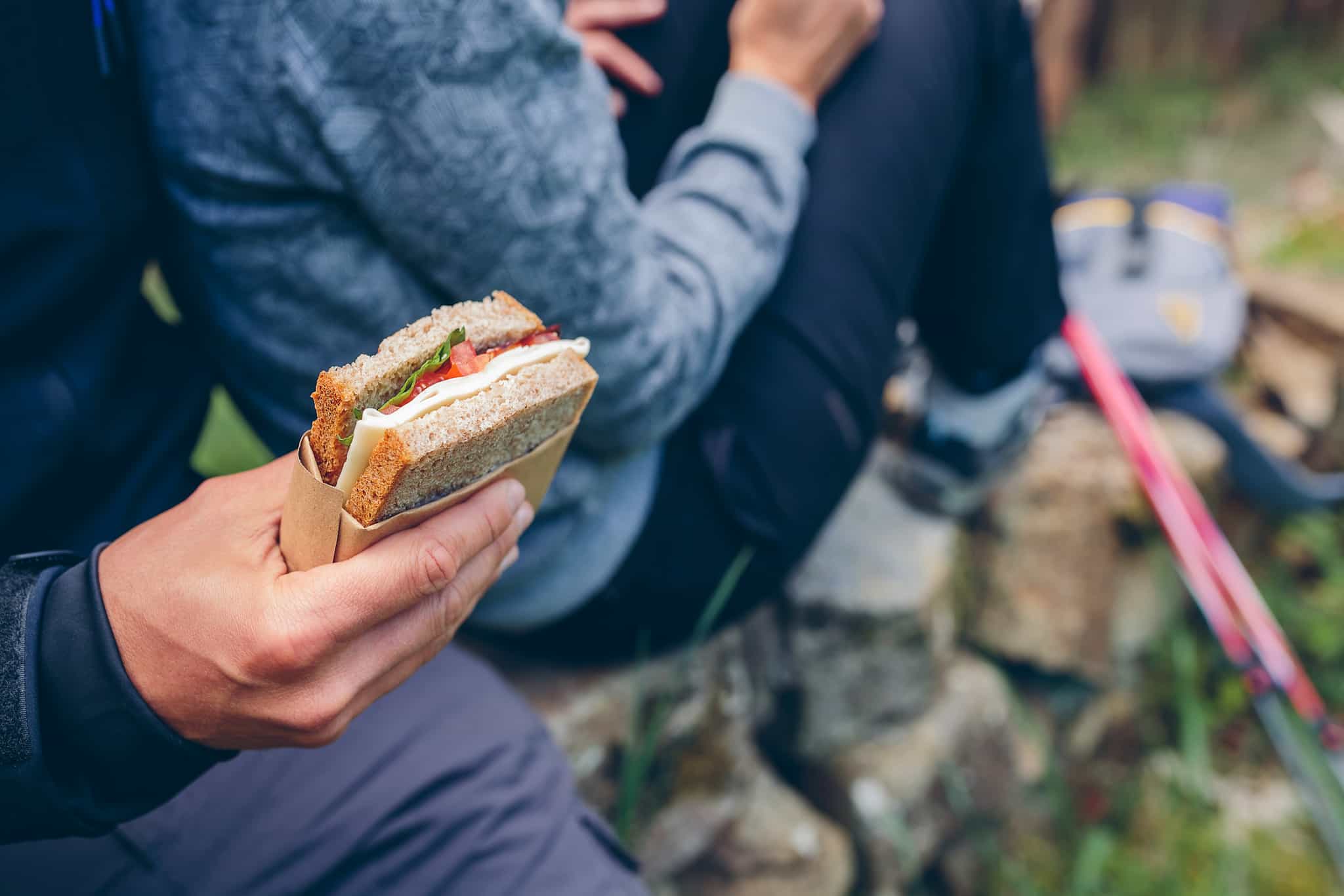 Hiker tucking into a sandwich on the trail