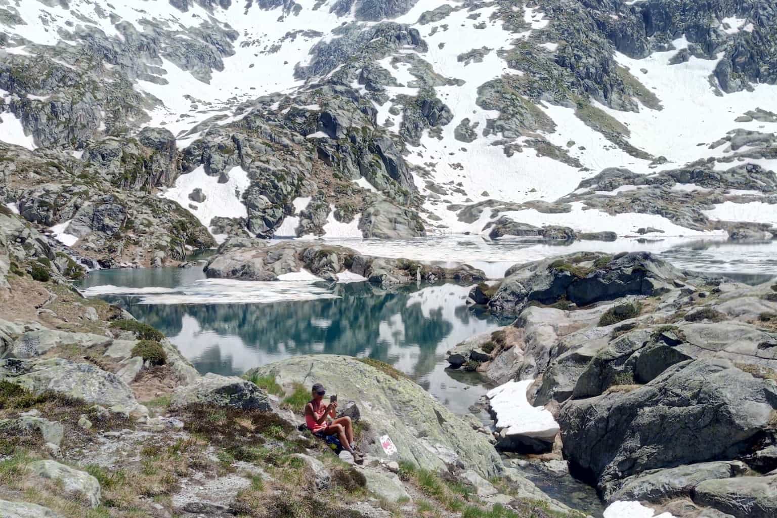 Hiker sits beside small lake in the Pyrenees