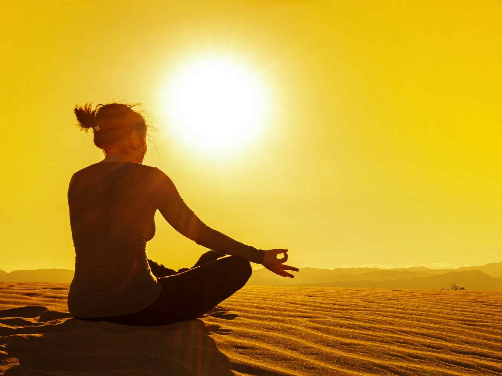 A female practises yoga in the Sahara Desert at sunset. 