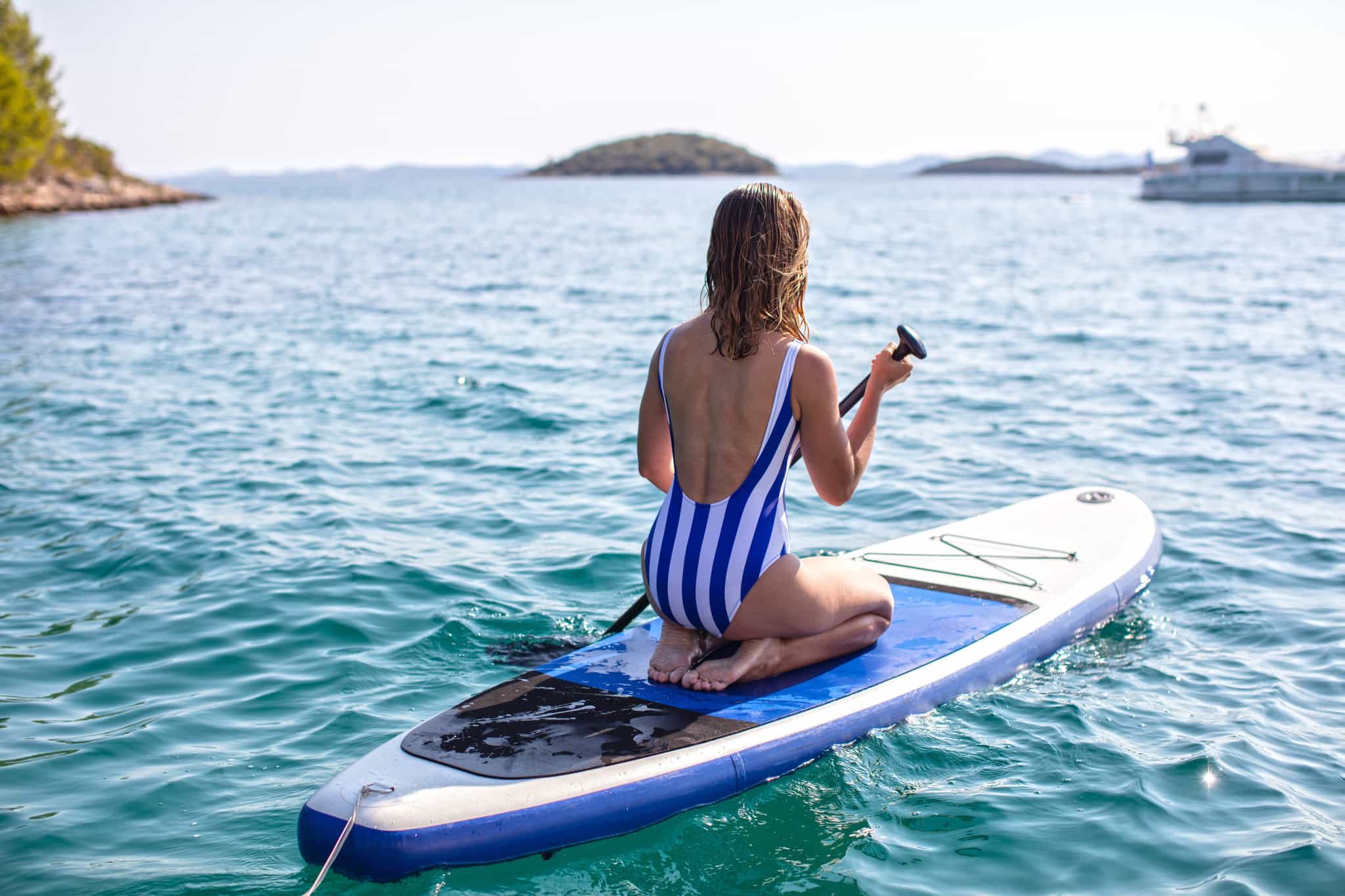Girl paddle boarding in the Cyclades, Greece.