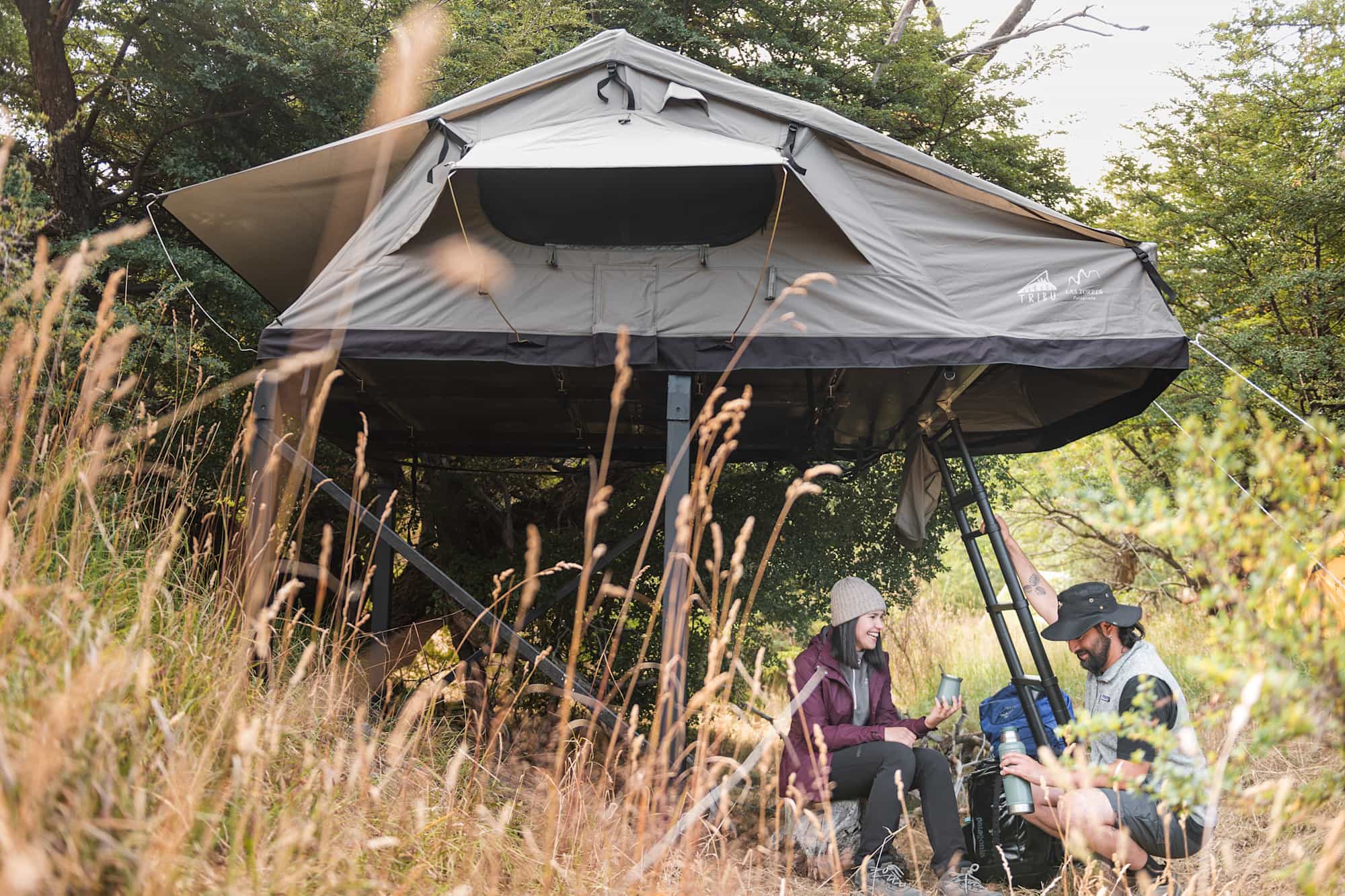 Two campers enjoying a rest below their raised tent in Torres del Paine