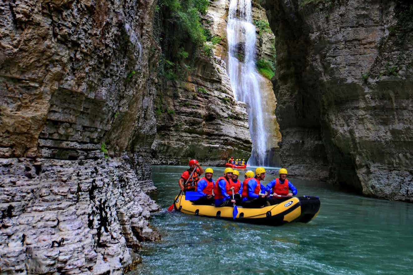 Rafters passing through the Osumi Canyon with a waterfall in the background, Albania.