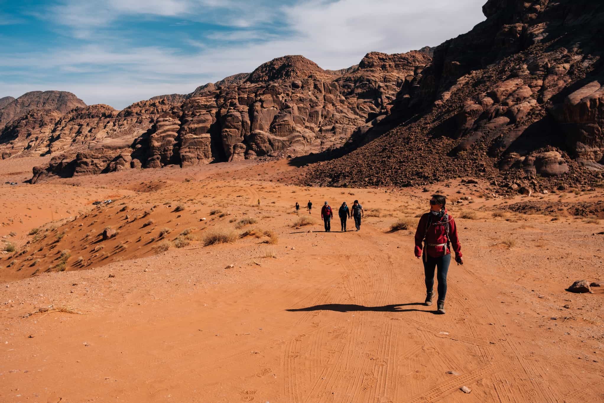 Hikers walking through the red sand landscape of Wadi Rum in Jordan.