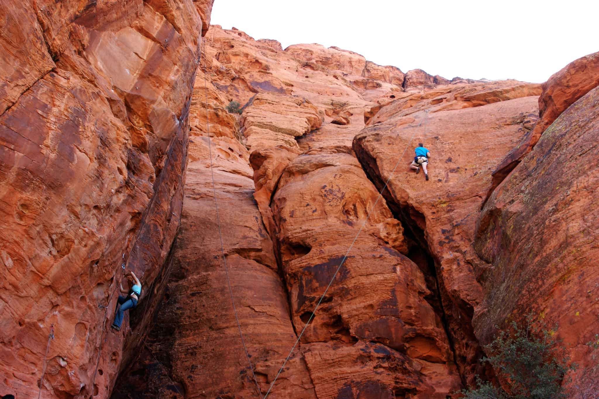Two rock climbers ascend the red rock of Todra Gorge, Morocco.