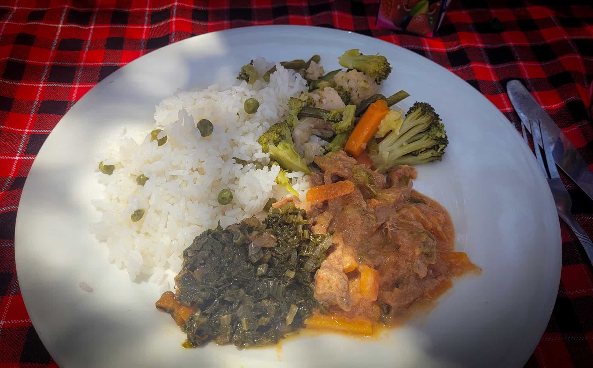 Plate of typical Tanzanian lunch including rice, curry and vegetables.