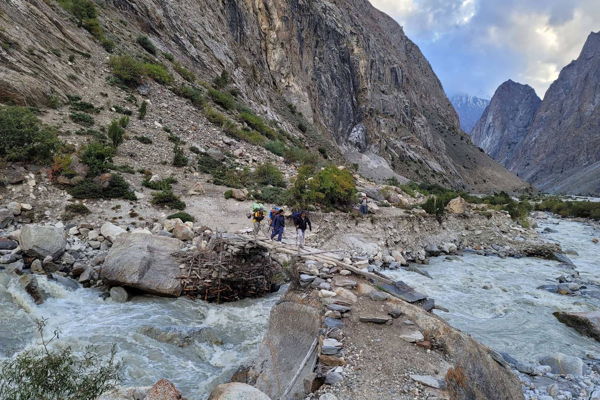 Hikers cross a river in the Charakusa Valley
