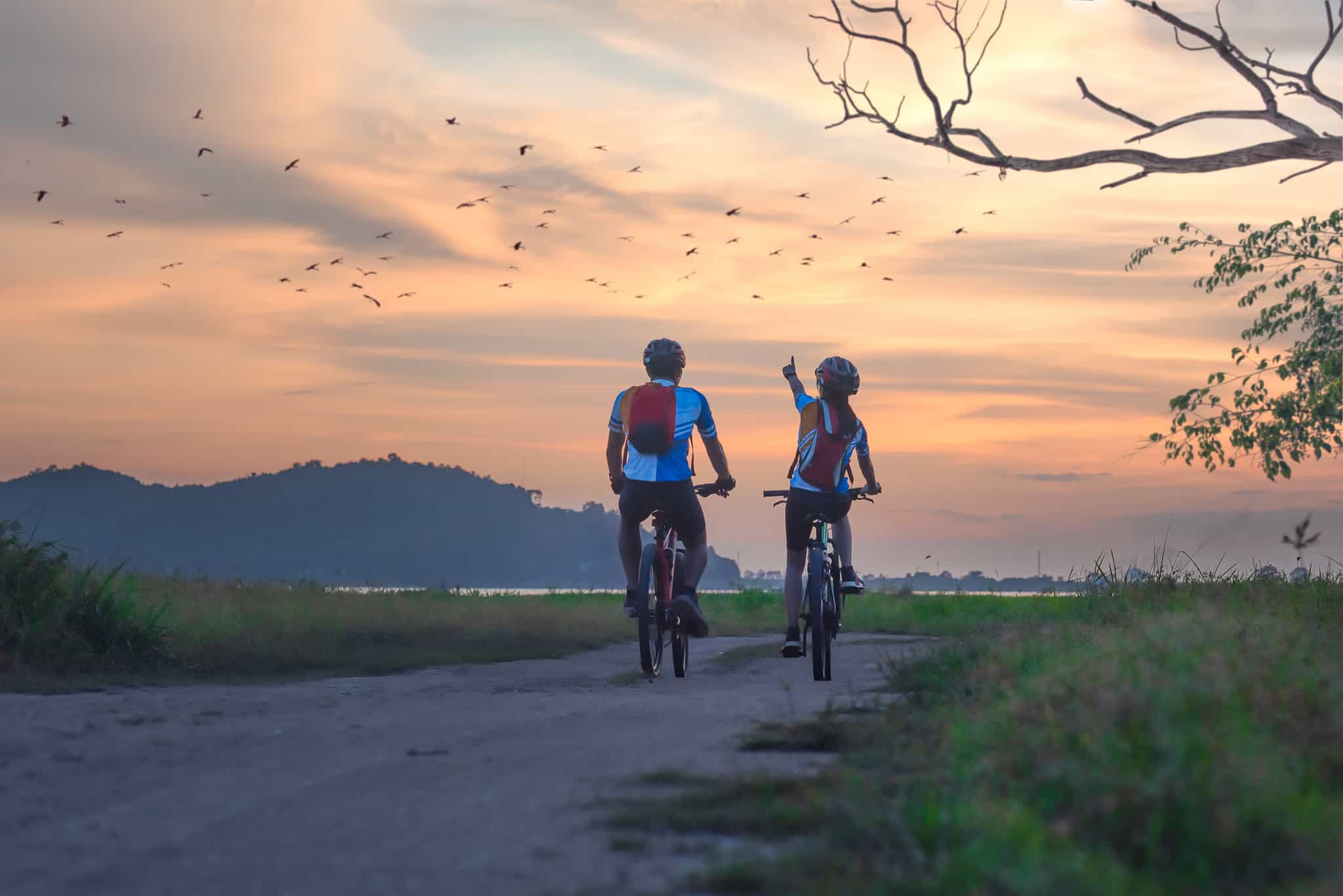 Couple cycling by a lake at sunset