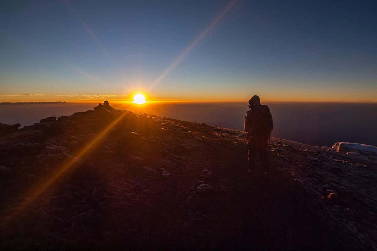 Silhouette of a hiker at sunrise on top of Kilimanjaro, Tanzania.