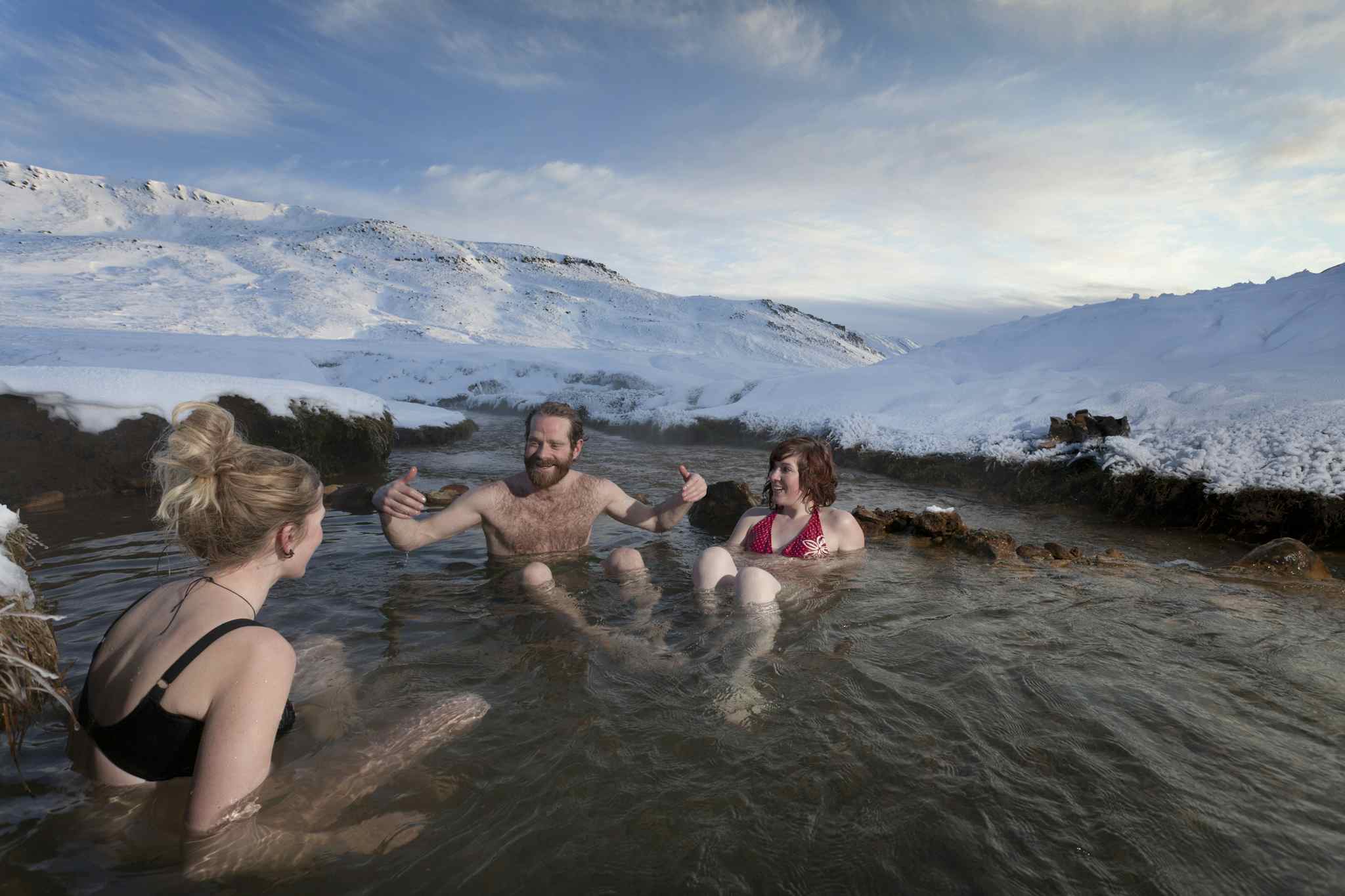Friends relaxing in glacial hot spring, Iceland. Photo: GettyImages-143689808