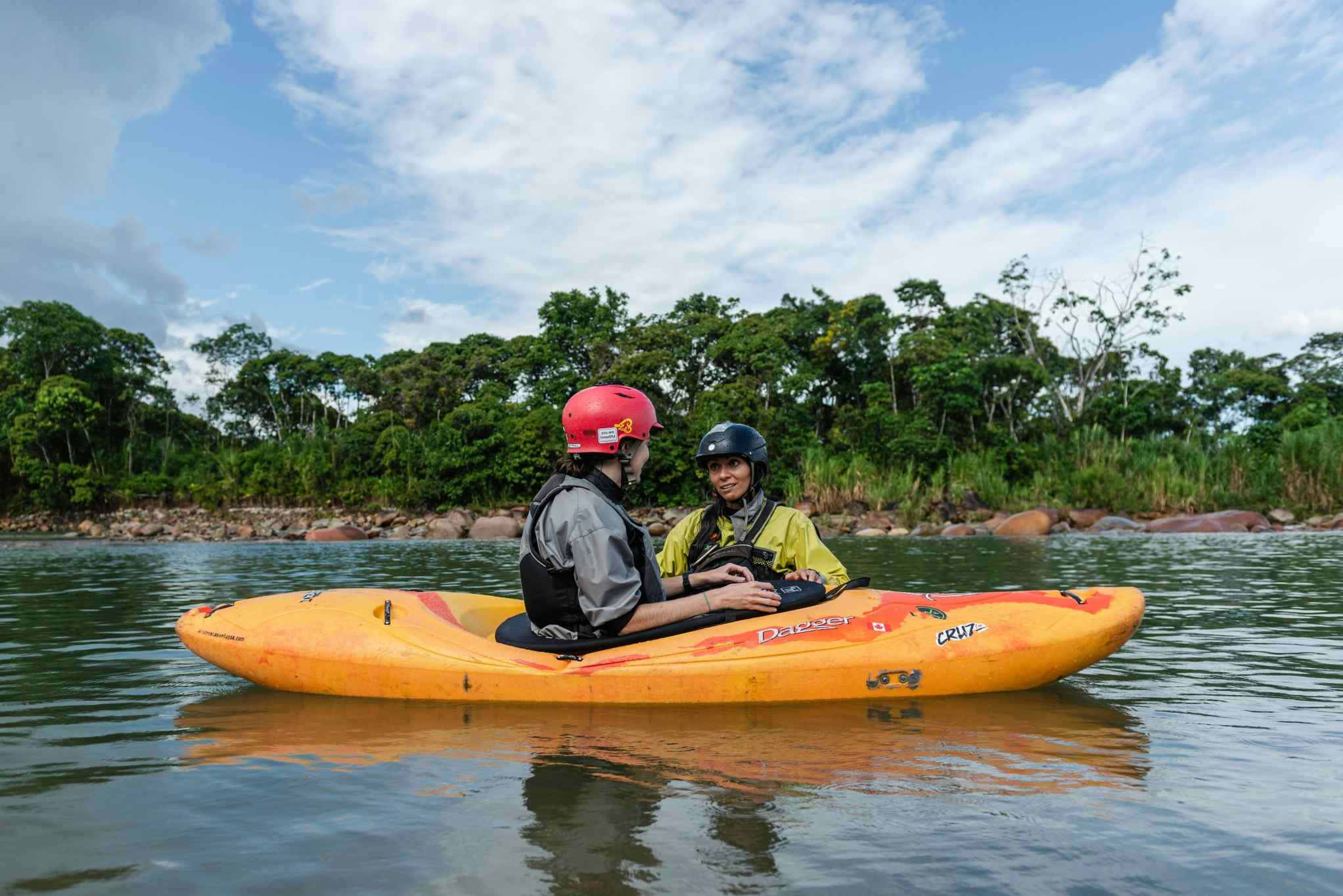 Two kayakers chatting on a river in the Amazon Basin, Ecuador. 