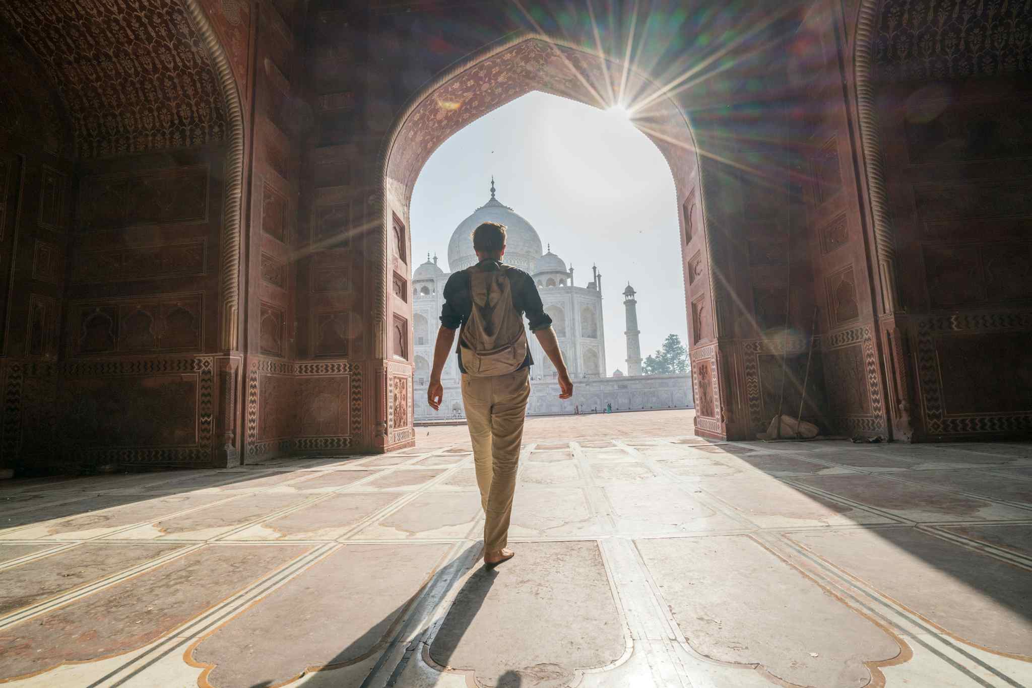 Young man contemplating the famous Taj Mahal at sunrise walking and wandering inside the marvellous monument. Photo: GettyImages-1085852158