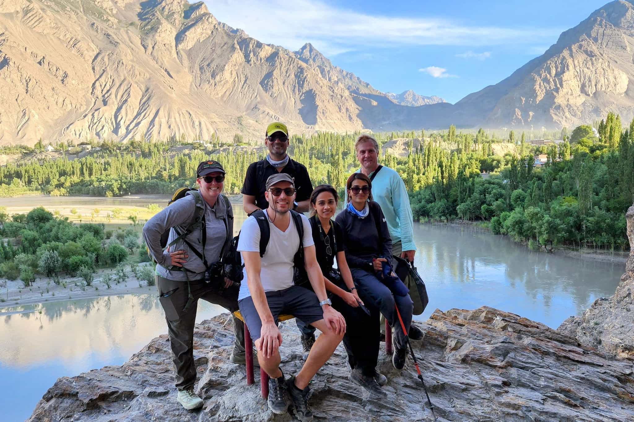 Group posing for a photo from a viewpoint above a lake in Skardu