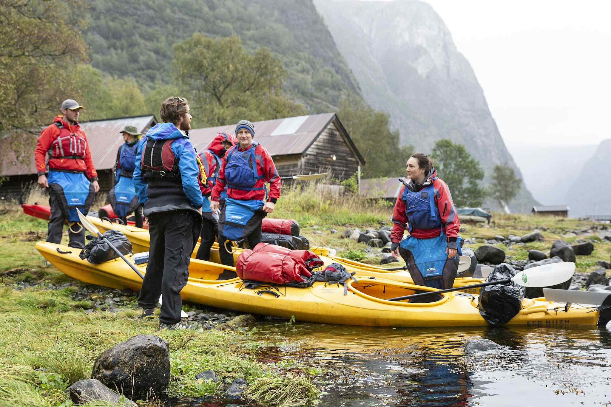 A group of kayakers prepare their kayaks on the edges of the Naeroyfjord in the Norwegian Fjords. 