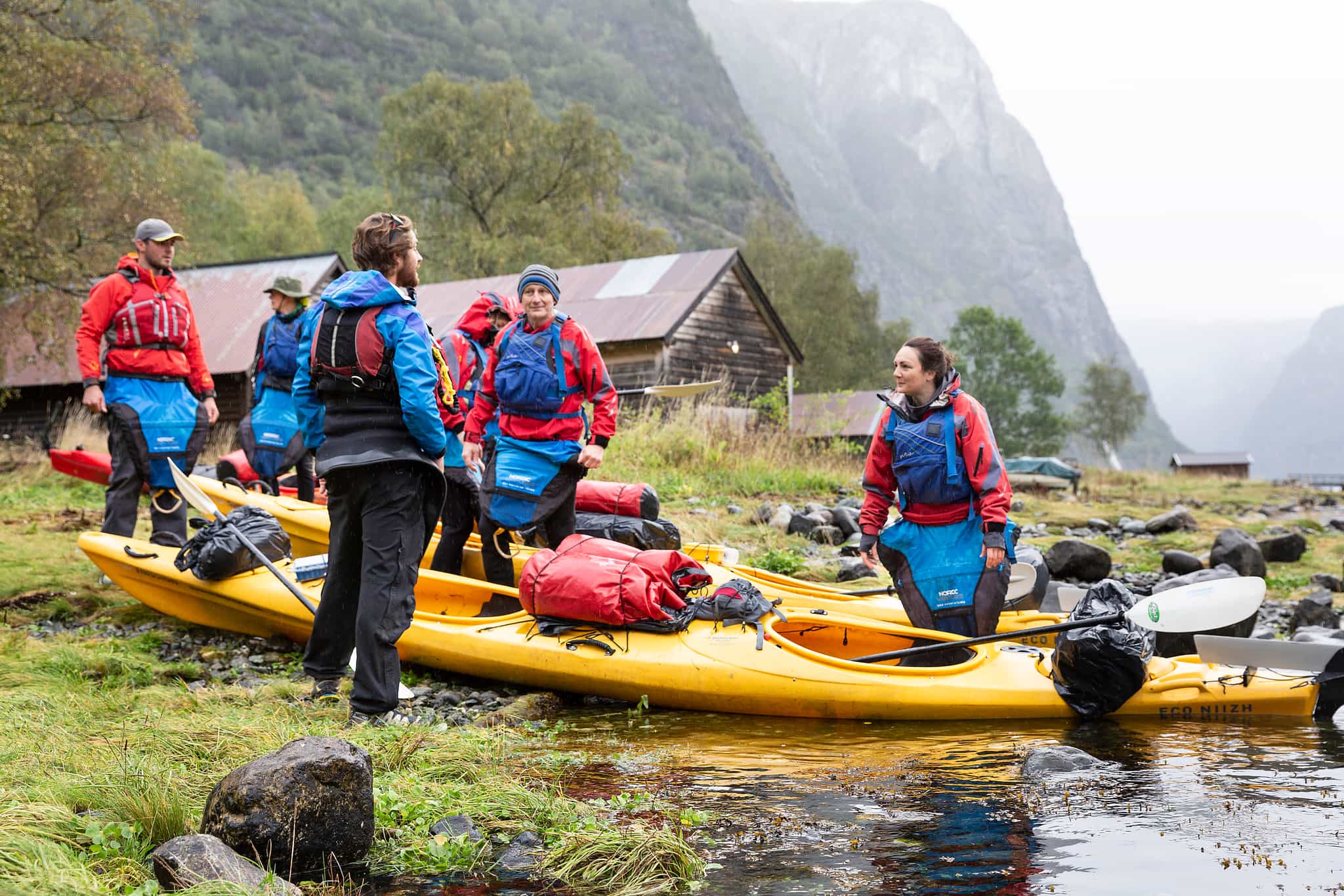 A group of kayakers prepare their kayaks on the edges of the Naeroyfjord in the Norwegian Fjords. 