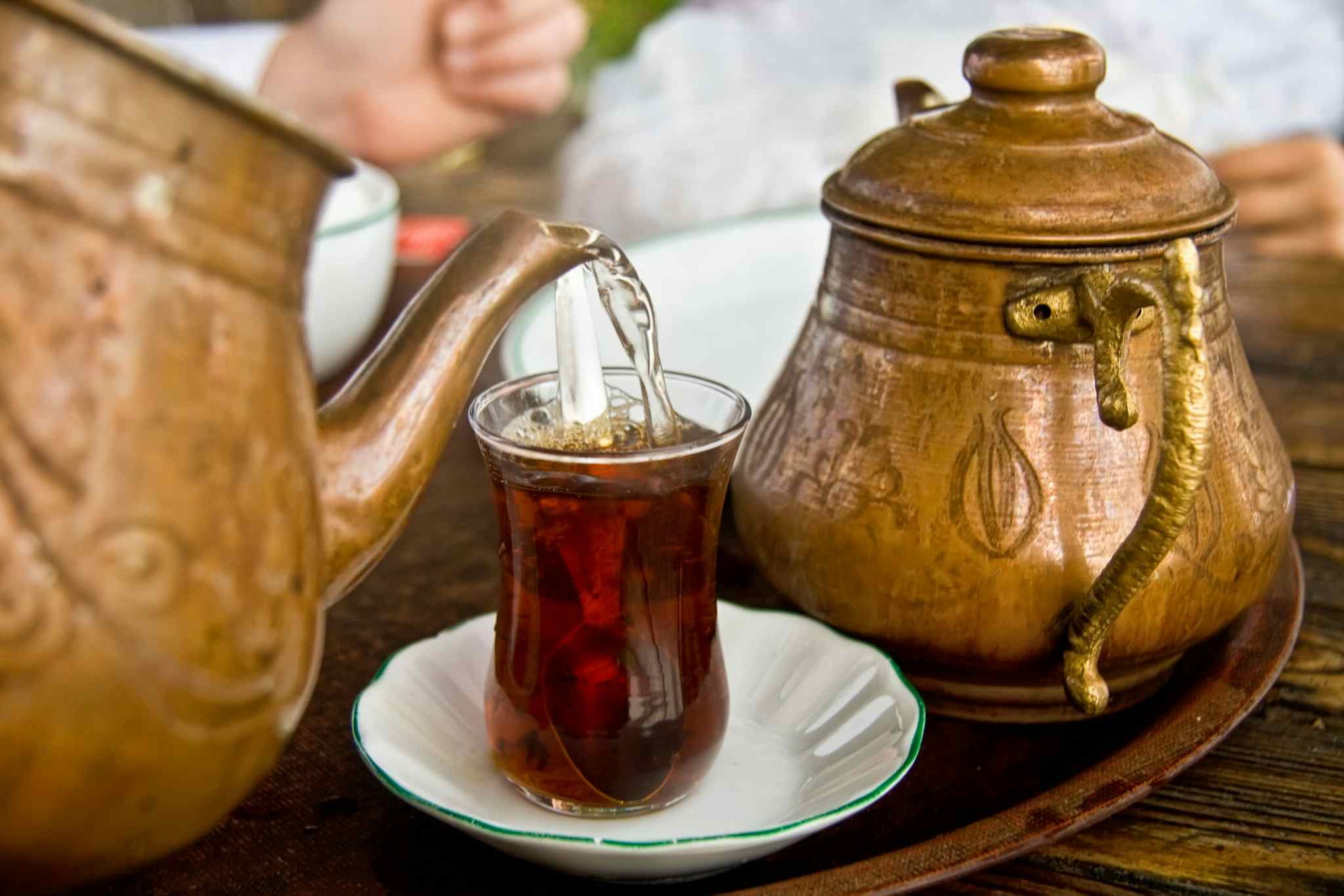 Drinking traditional Turkish Tea with Turkish tea cup and copper tea pot shutterstock 121847368