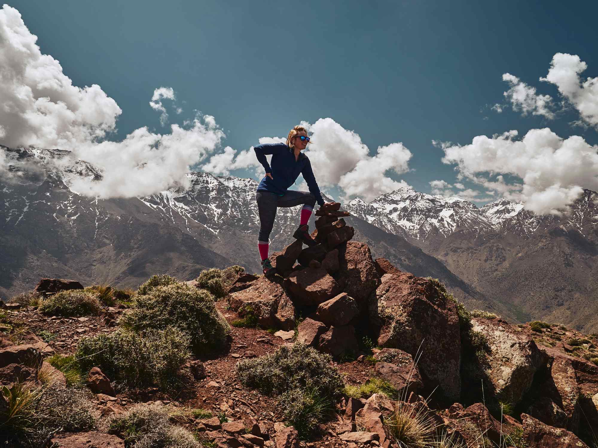 A woman leans against a rock on the rocky slopes of Mount Toubkal, Morocco. 