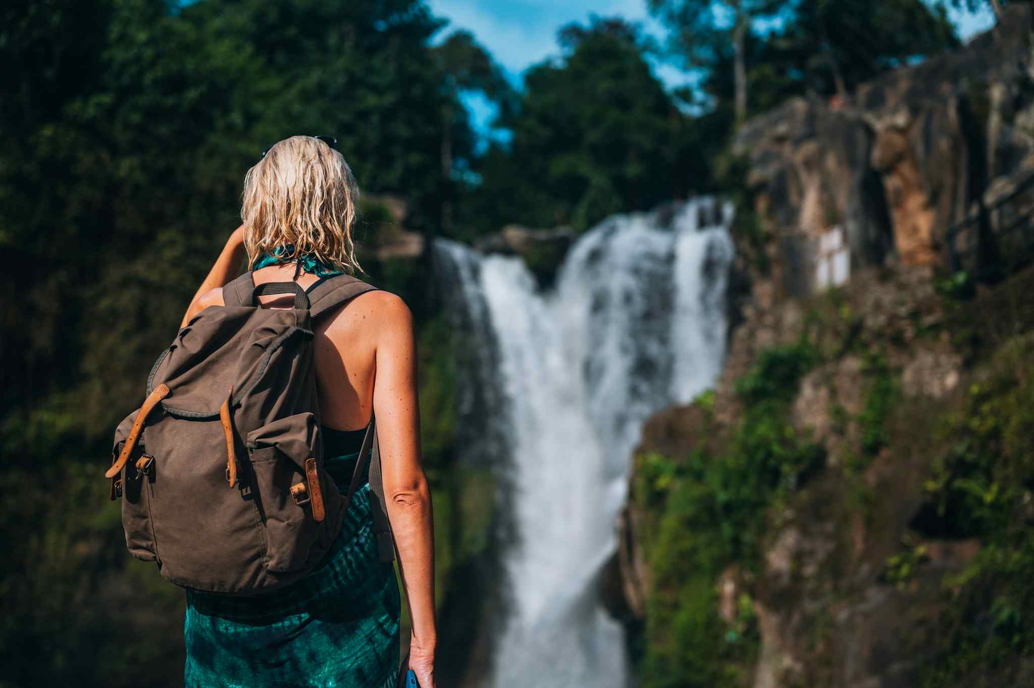 Female hiker looking at a waterfall in Bali, Indonesia