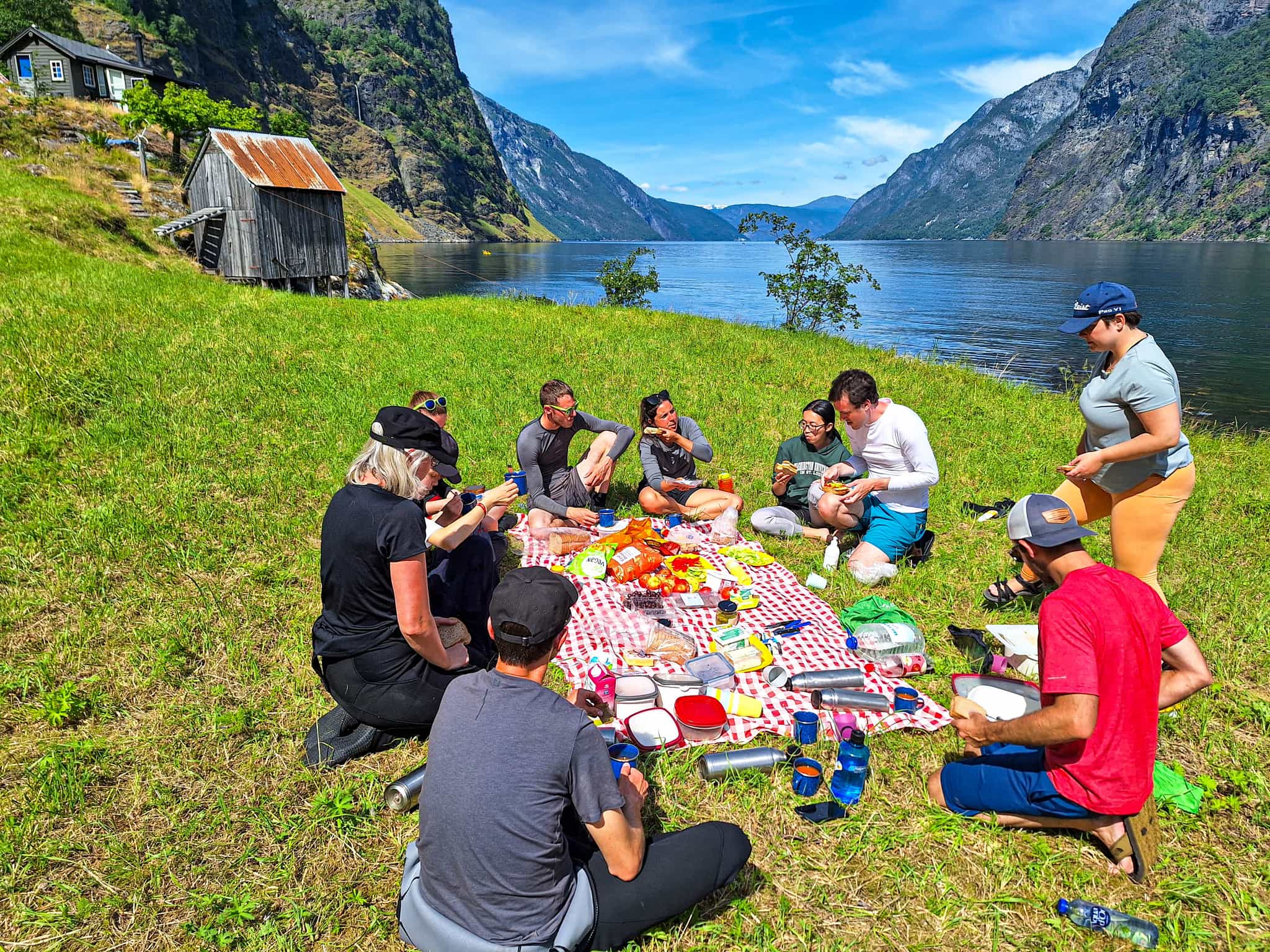 A group having a picnic in the sun at the edge of the Naeroyfjord in the Norwegian Fjords.