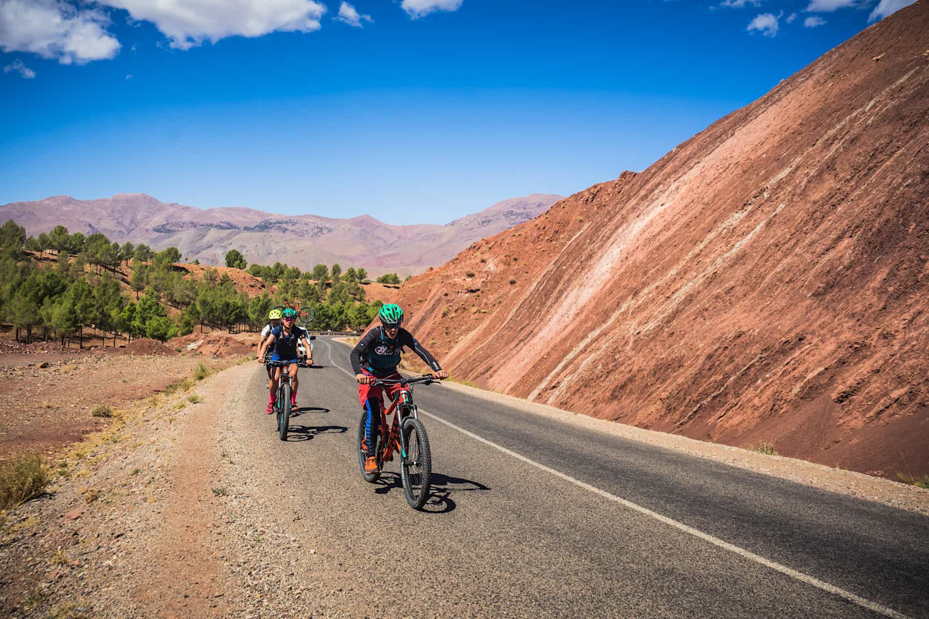 Cyclists riding down the road, with a hill on one side, Morocco