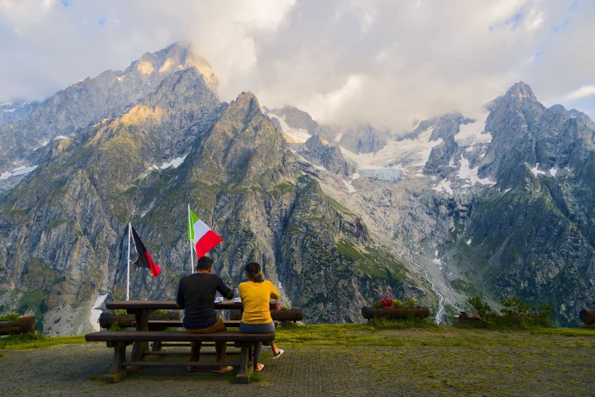 Couple sit on a bench overlooking the Val Ferret