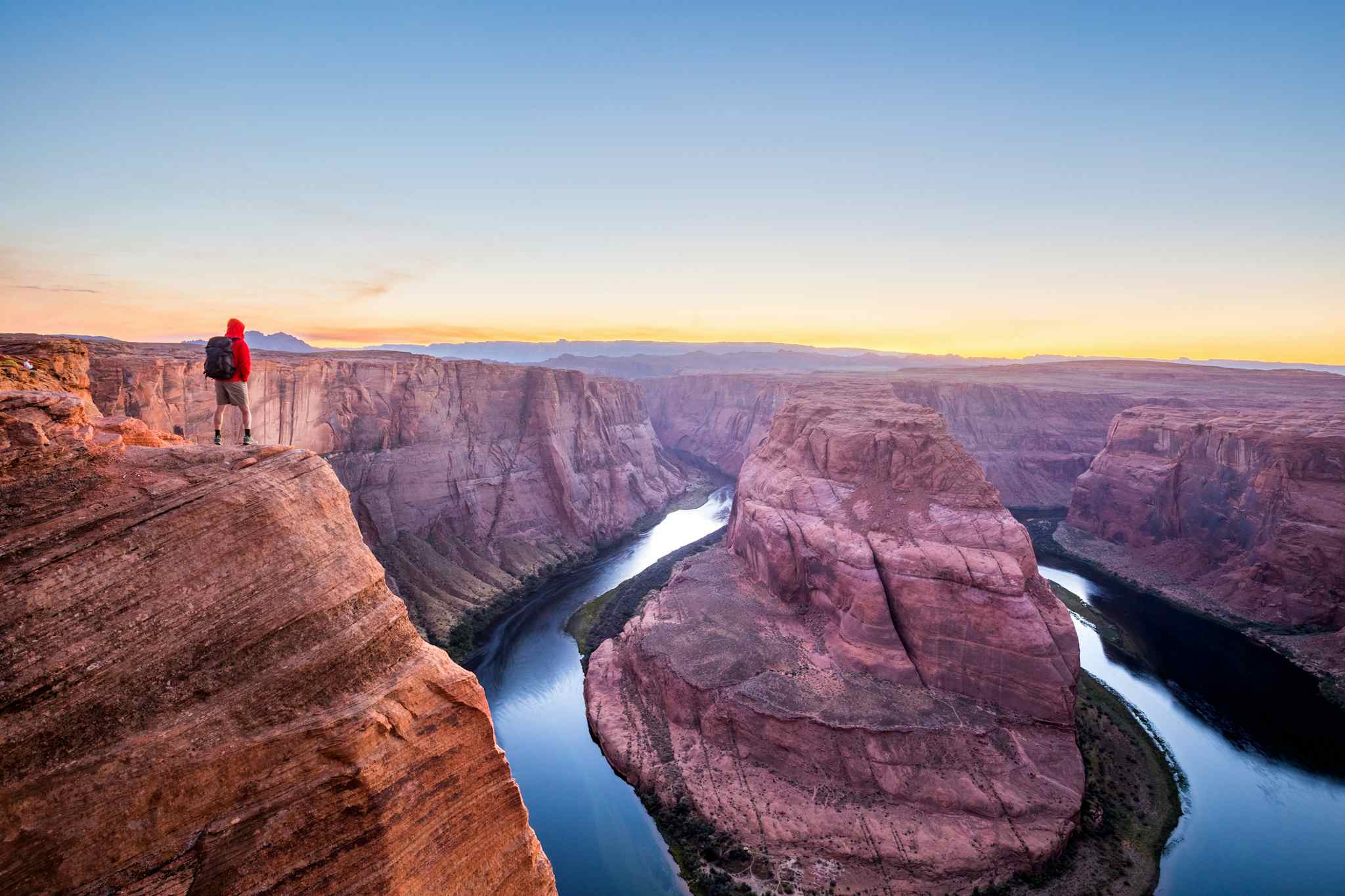 A male hiker is standing on steep cliffs enjoying the beautiful view of Colorado river flowing at famous Horseshoe Bend overlook in beautiful post sunset twilight on a summer evening, Arizona, USA

Getty: 683652564
