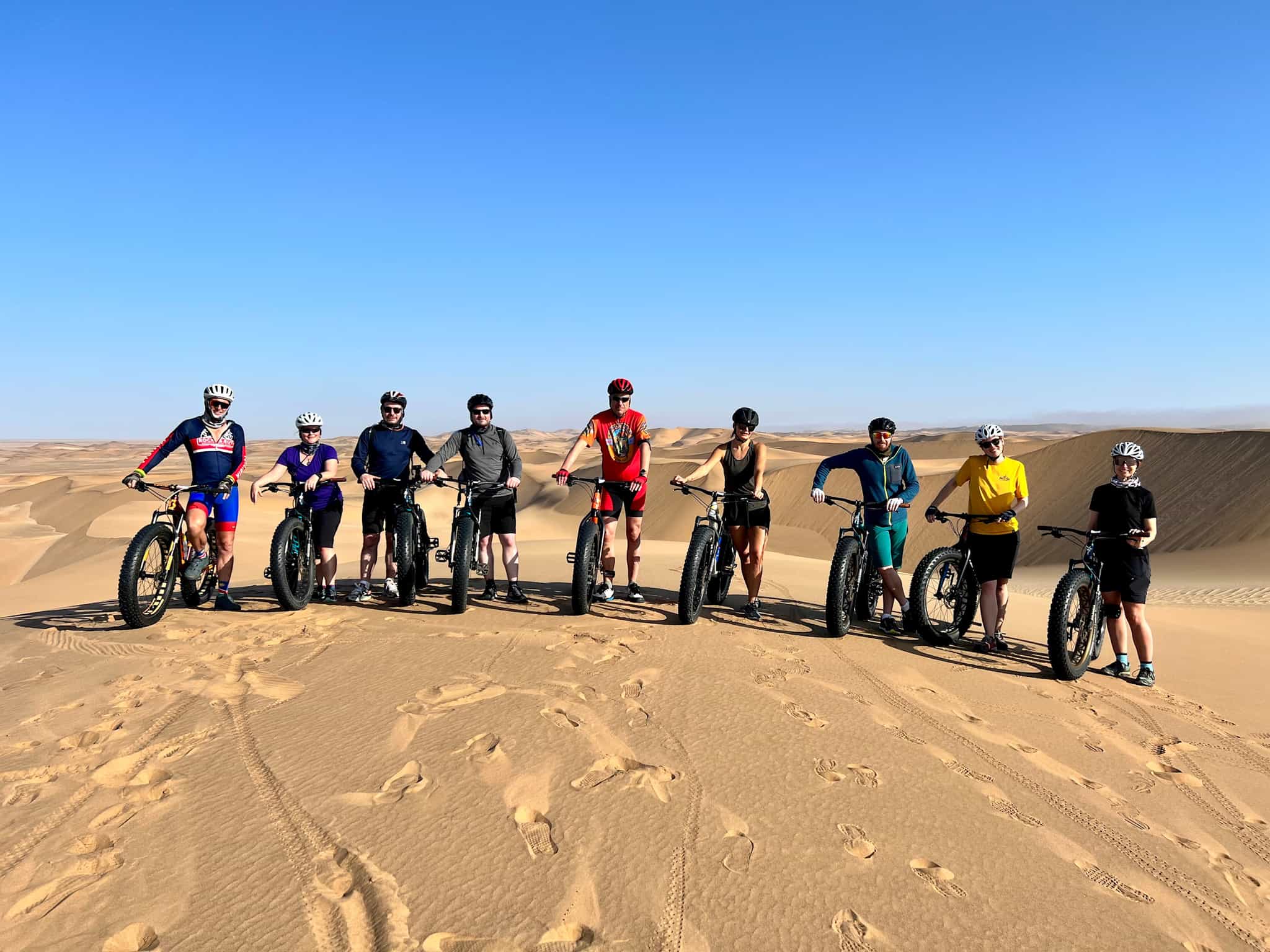 A group of cyclists on fat bikes in dunes of Namibia.