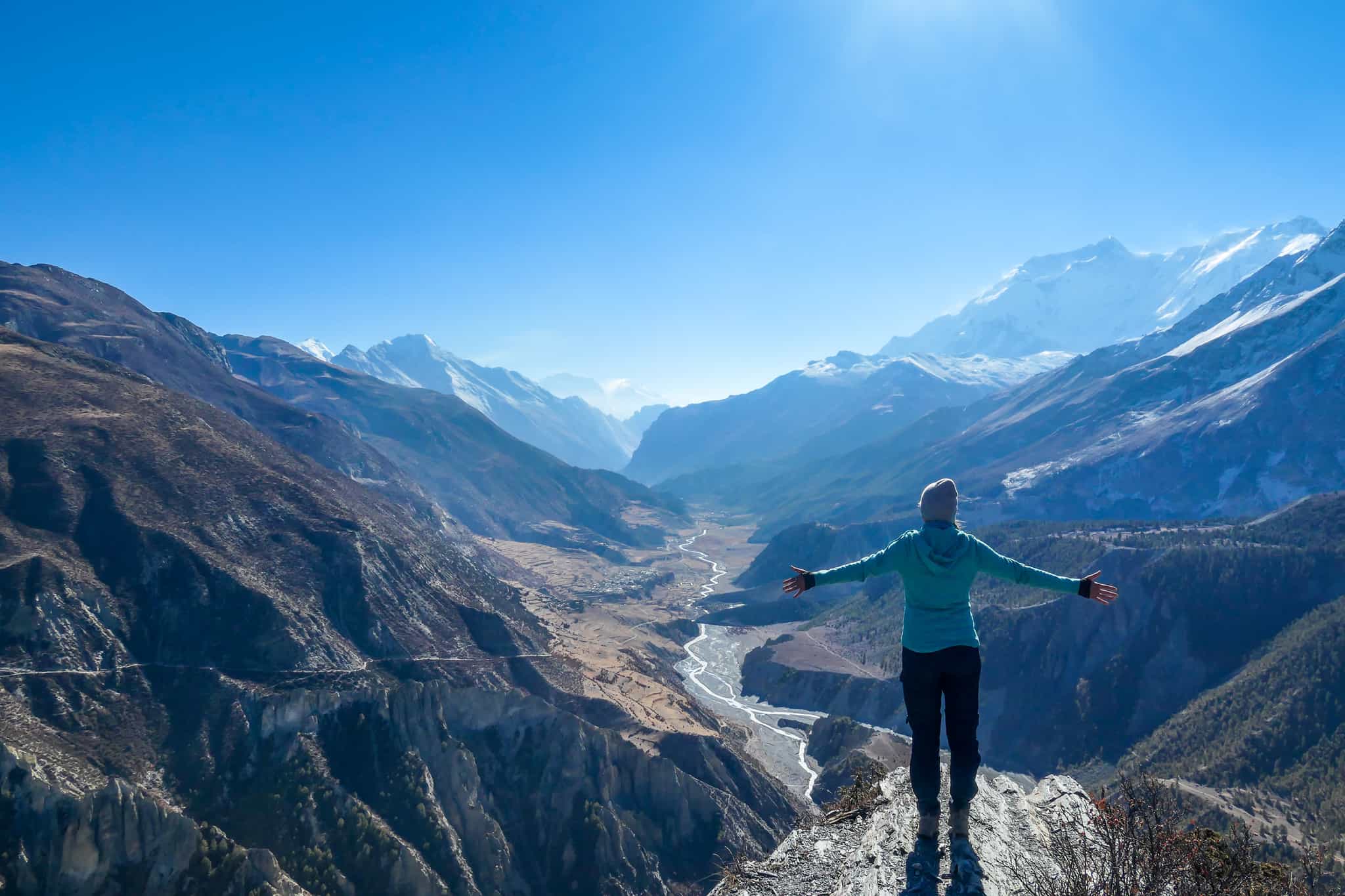 Woman overlooking river valley and mountains, Manang, Nepal. 