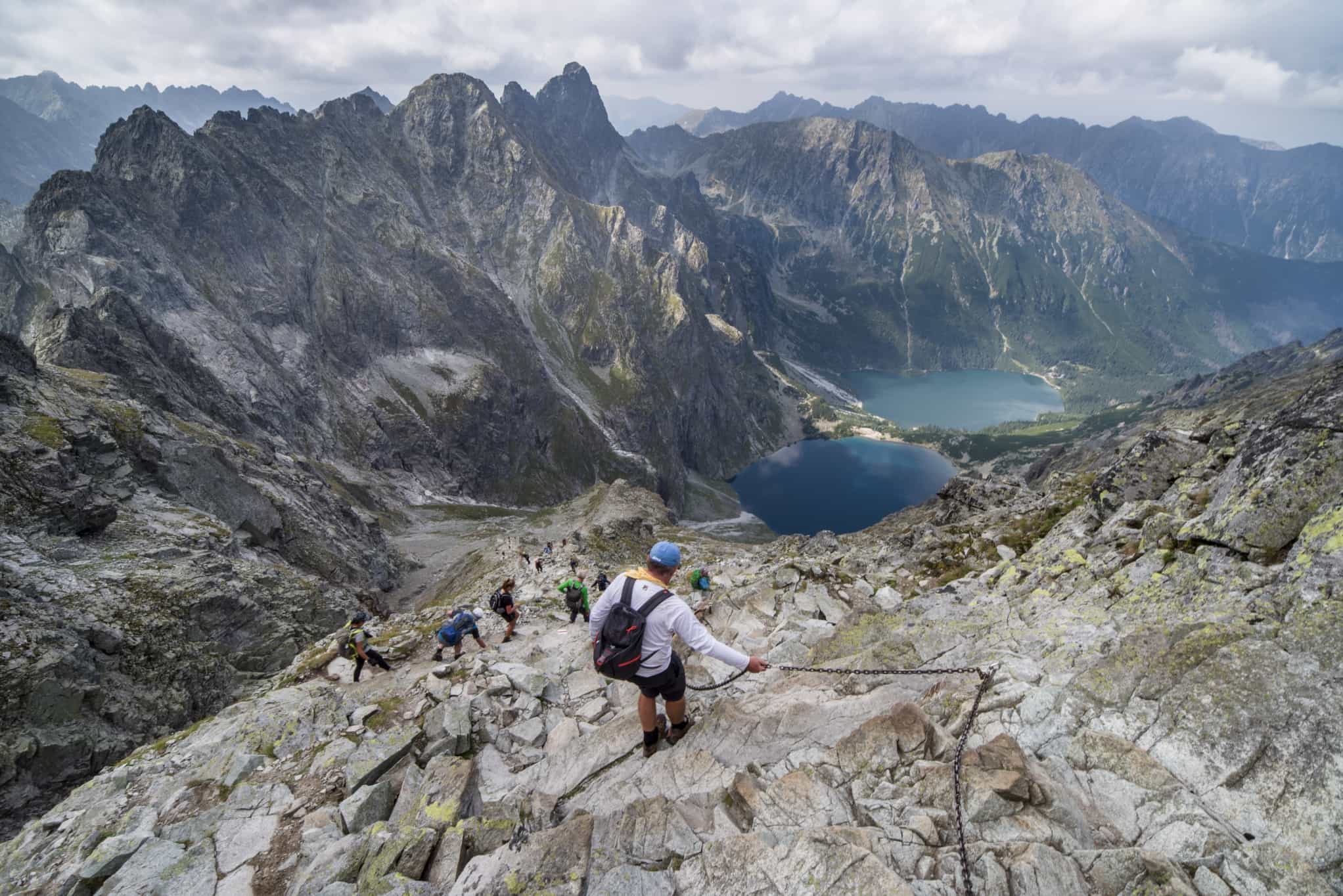 Hikers near the summit of Rysy with views over Morskie Oko and Szarny Staw lakes in Poland