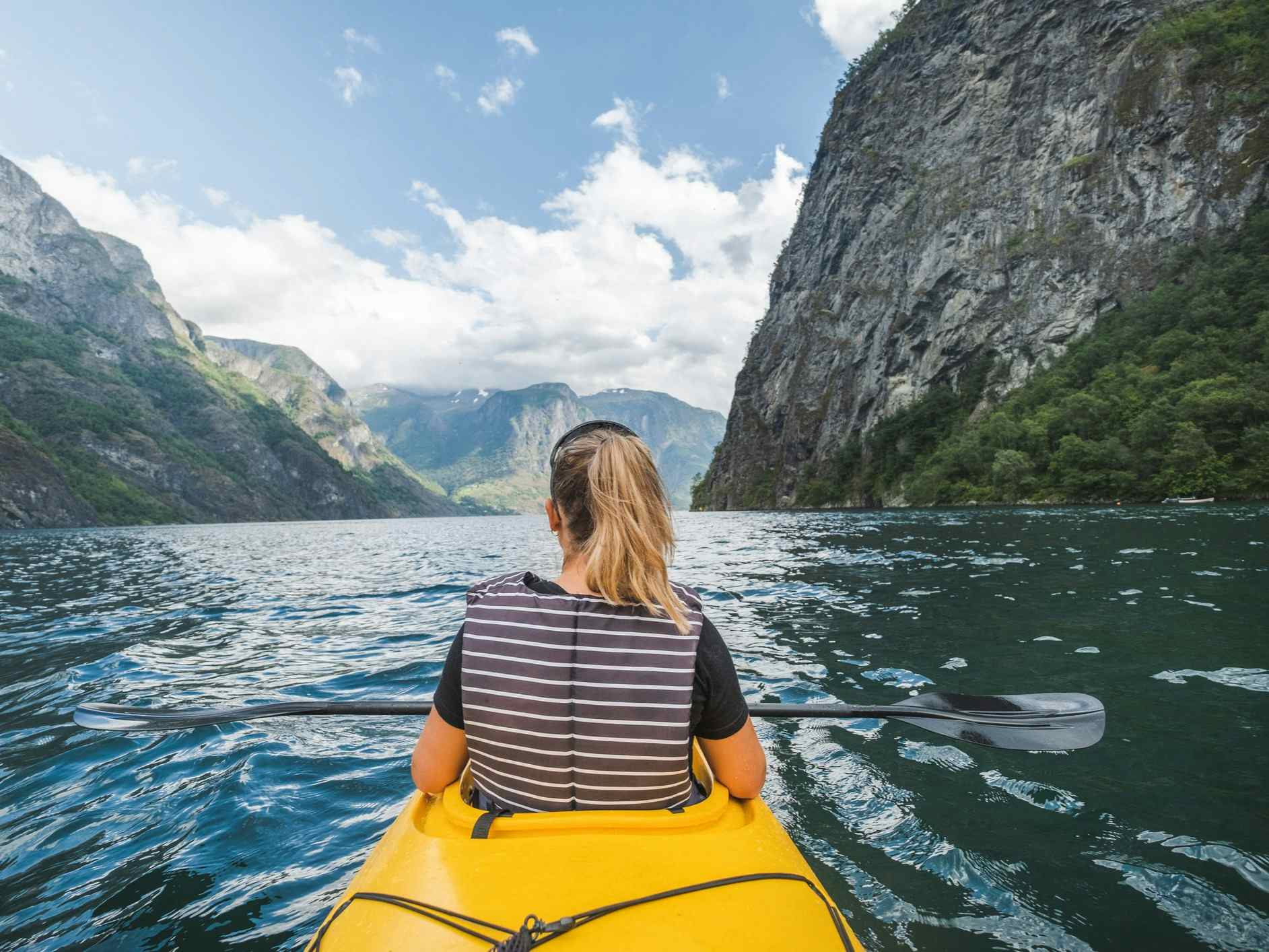 A woman paddles through the Naeroyfjord in the Norwegian Fjords. 