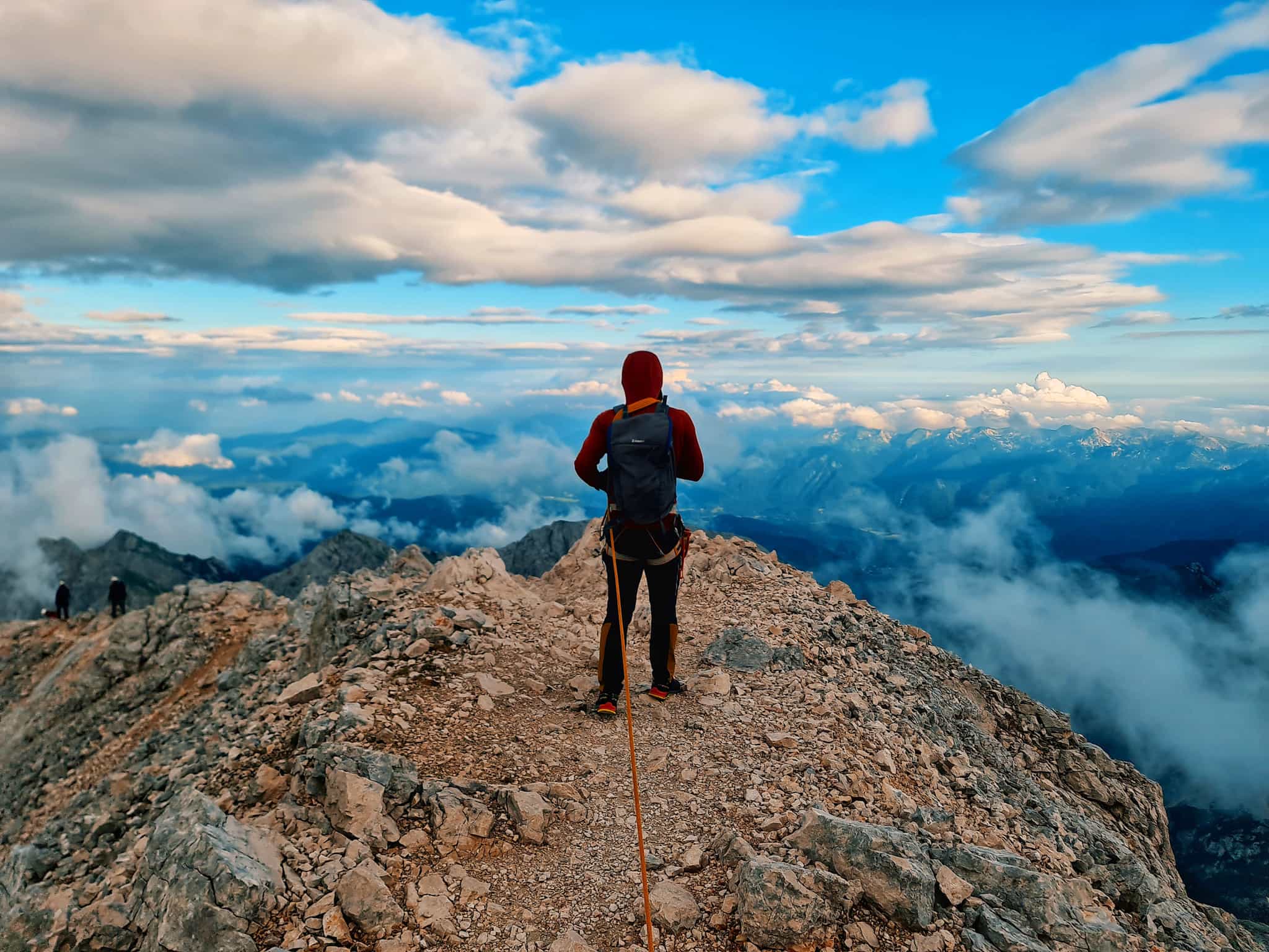 Roped hiker looking at the view from the summit of Mount Triglav in Slovenia.